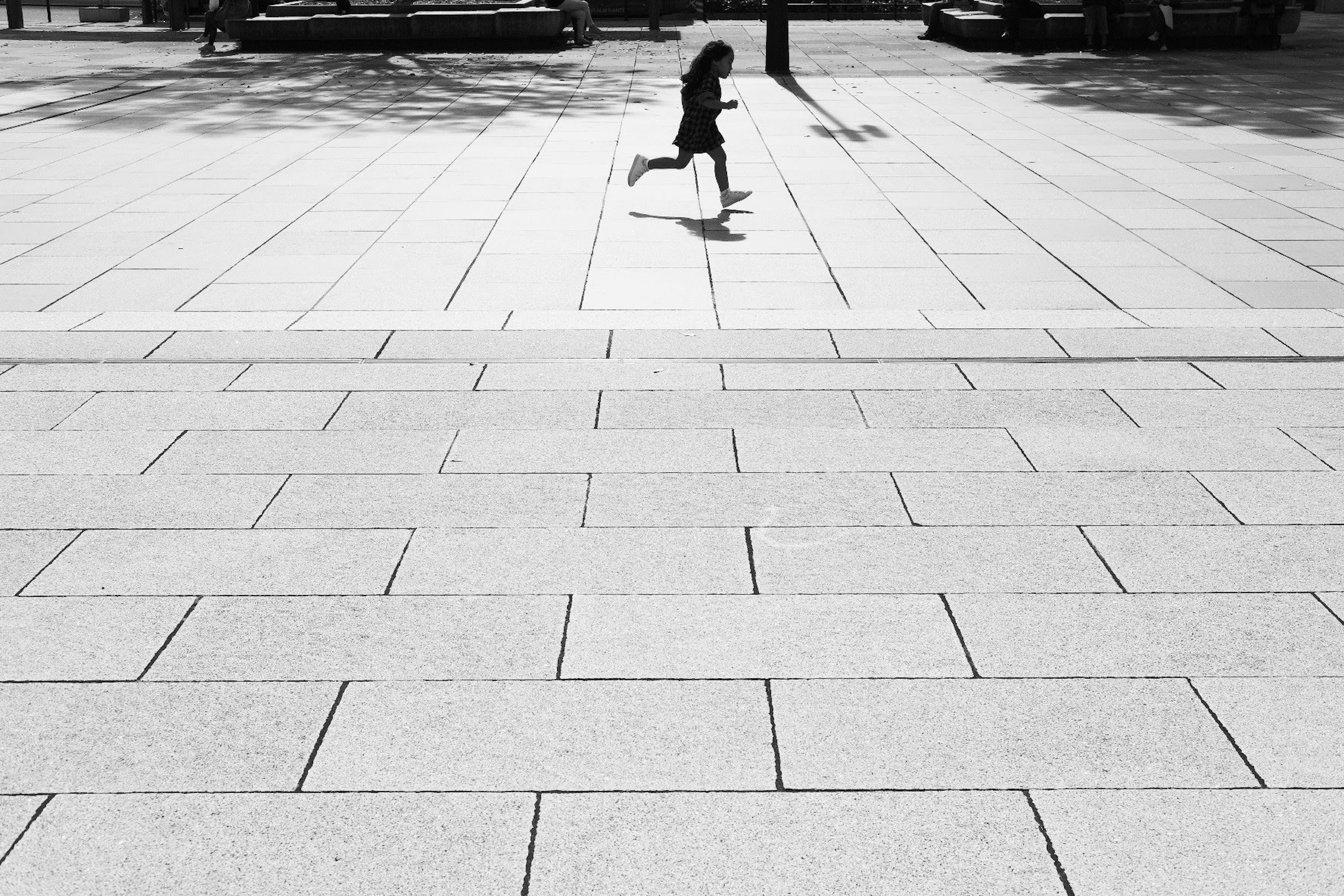 Silhouette of a child running on a plaza in black and white