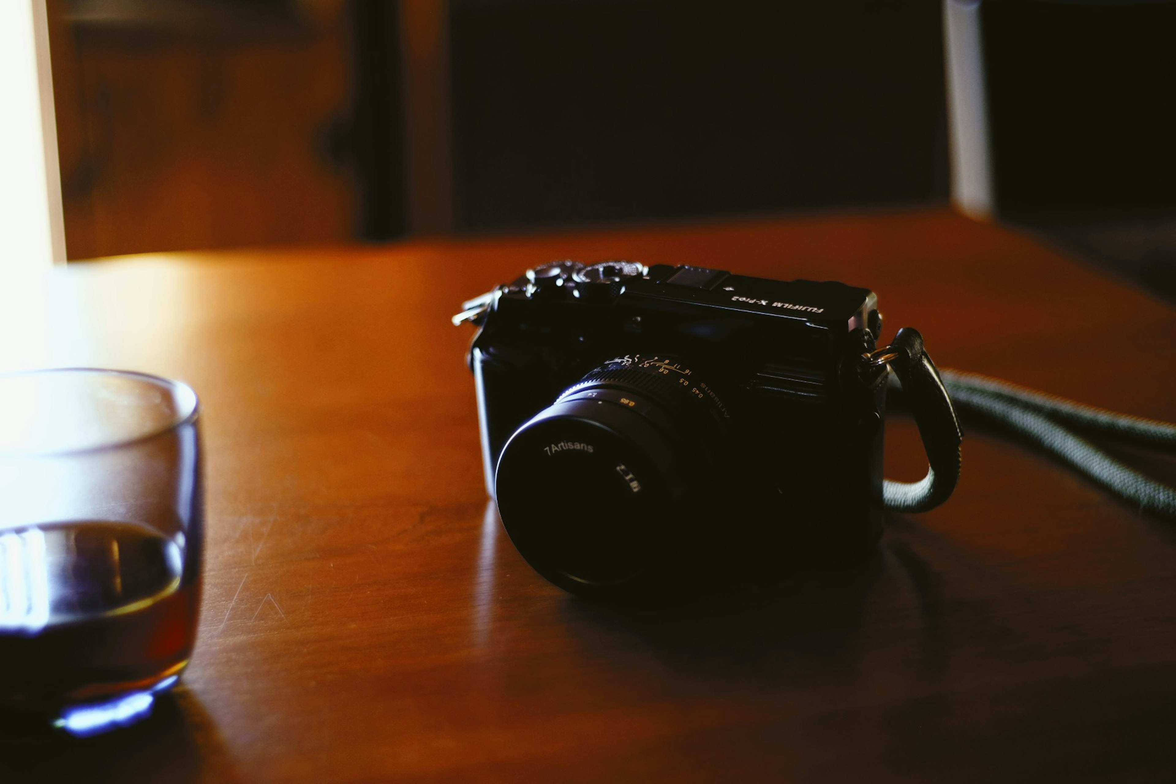 Scene of a camera and a glass on a wooden table