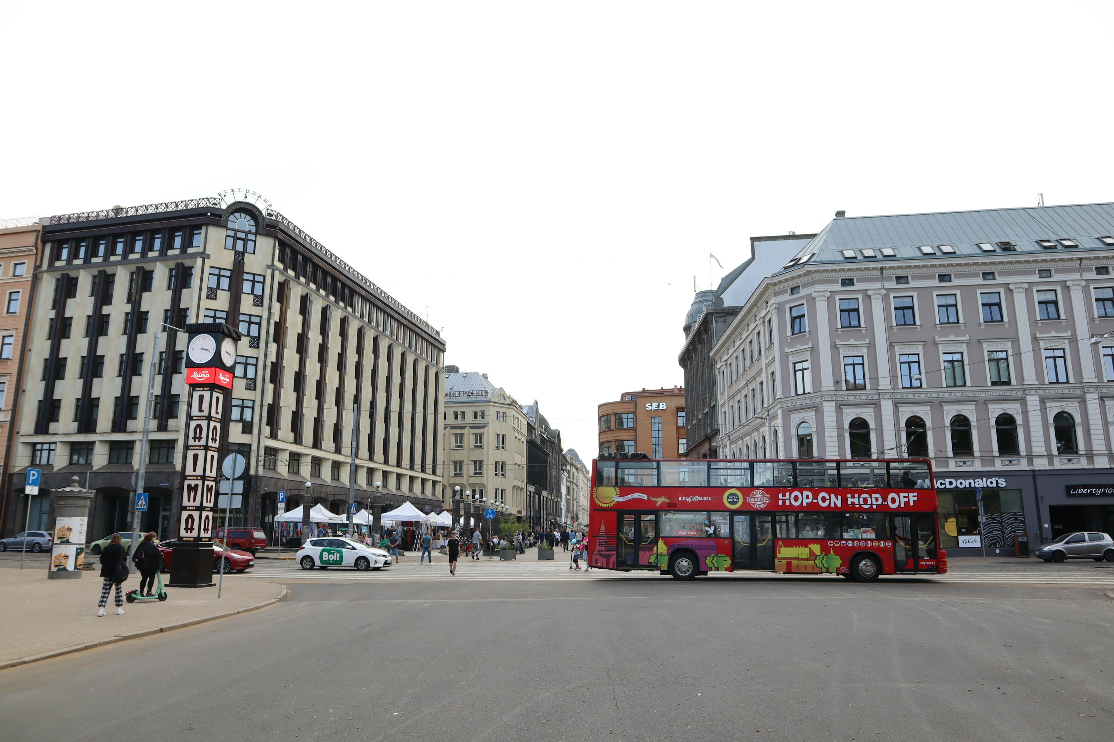 A red tourist bus parked in a square with historic buildings