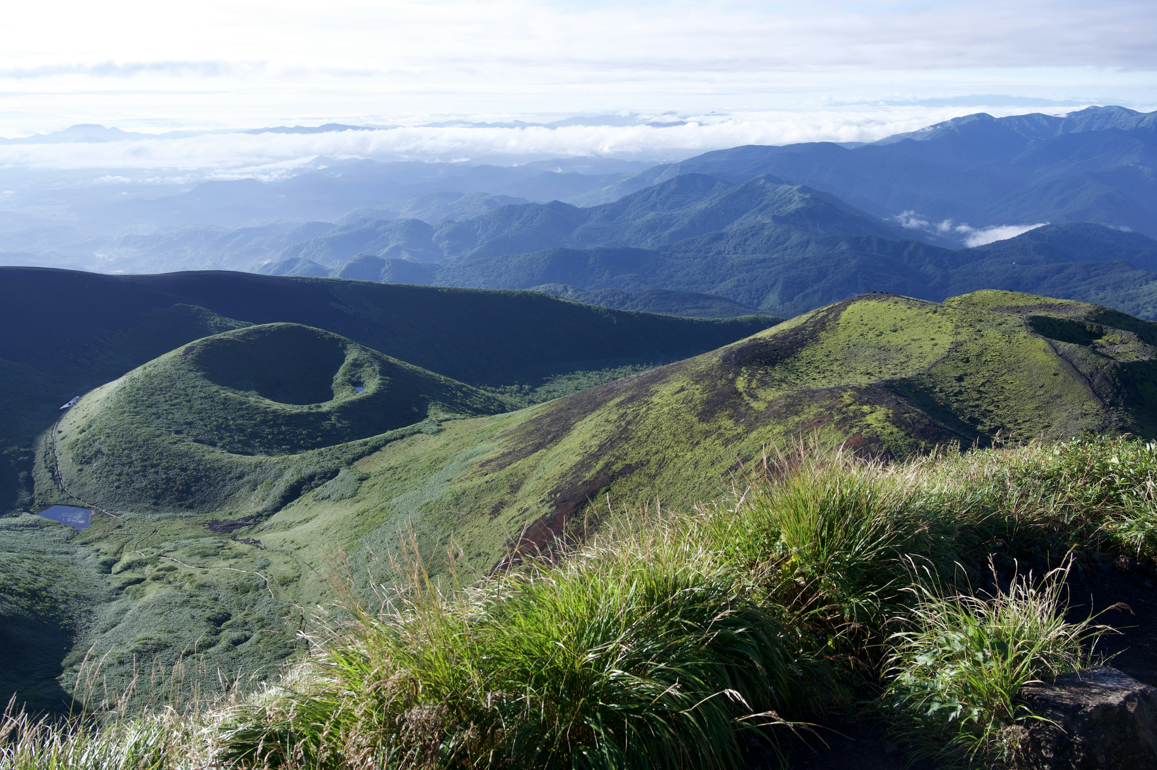 Vista escénica de colinas verdes con un mar de nubes al fondo