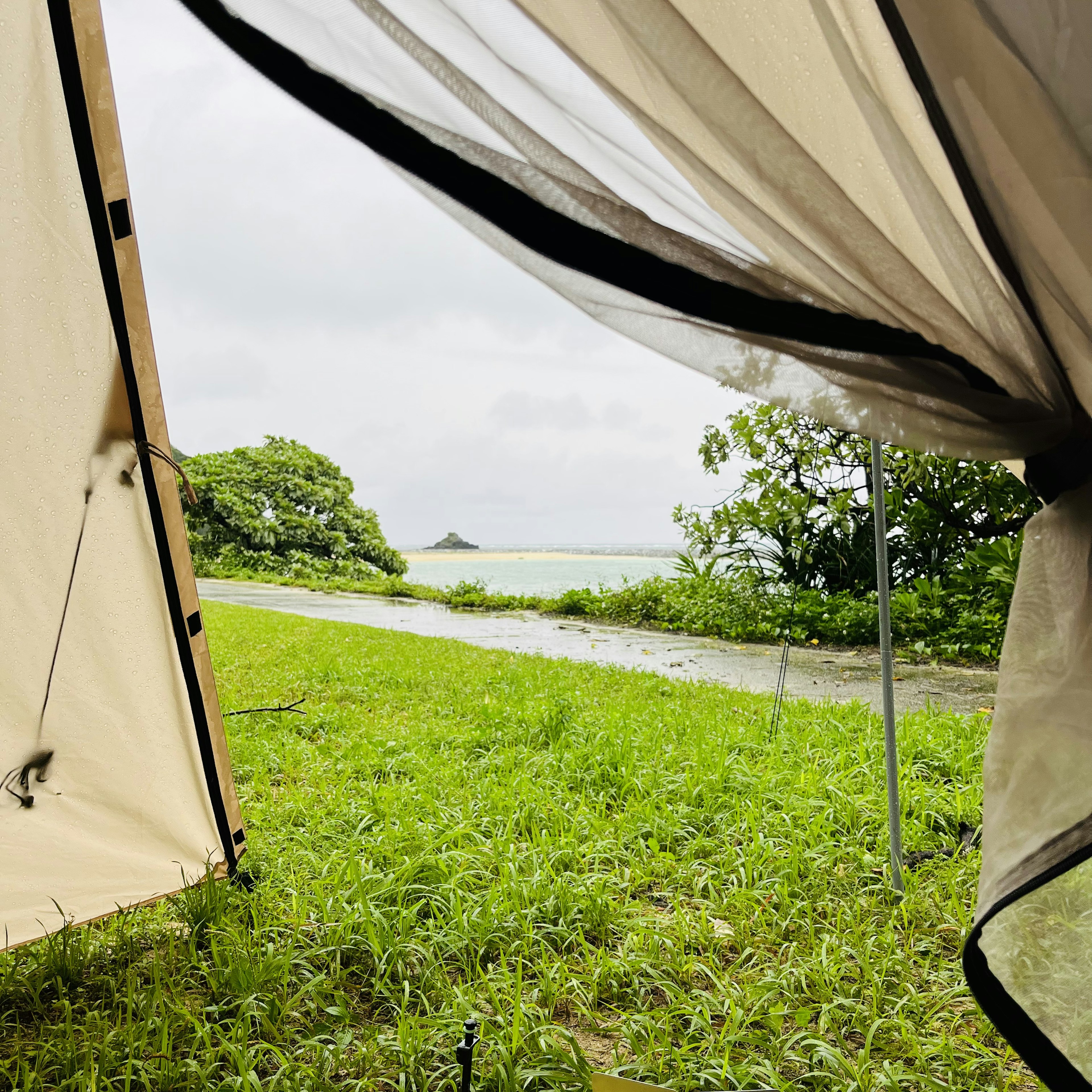 Vista da una tenda con erba e oceano sotto un cielo nuvoloso