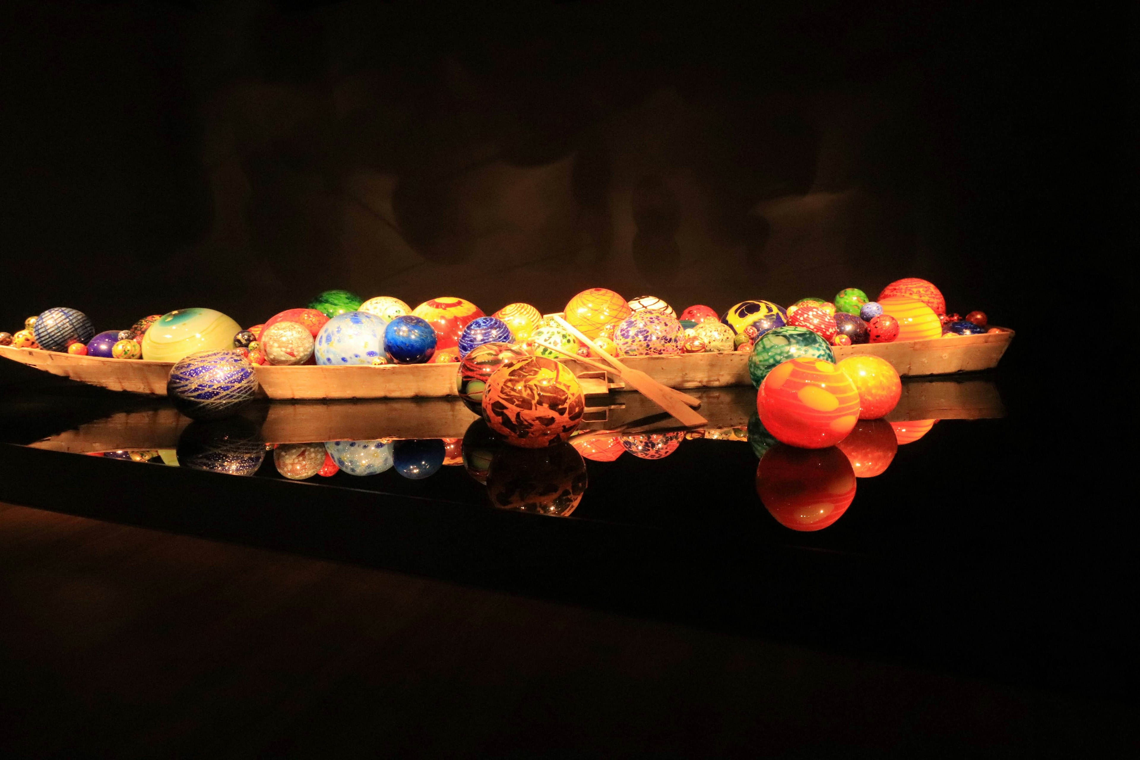 An array of colorful glass orbs displayed on a reflective surface