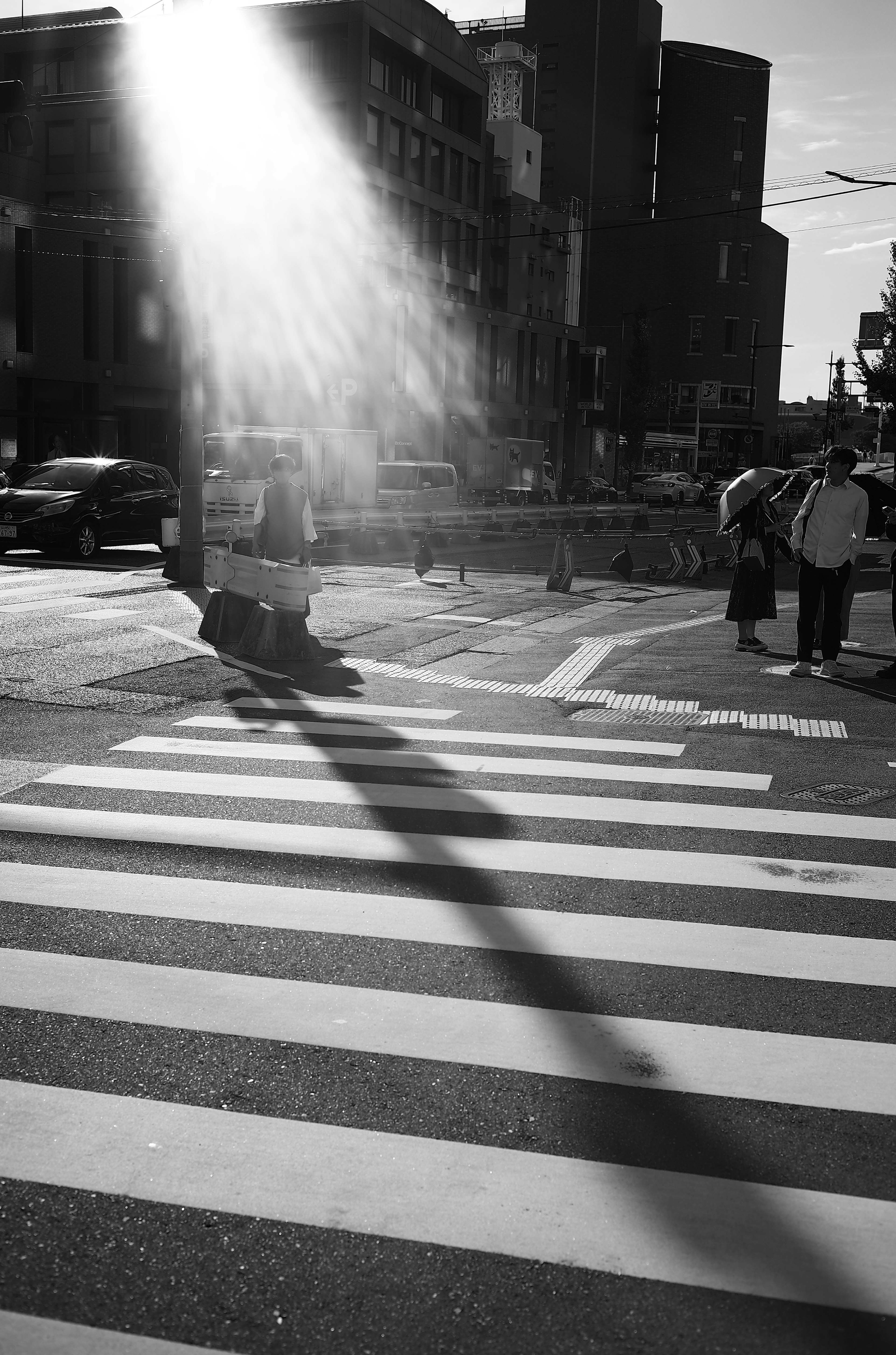 Black and white crosswalk with people walking and a beam of light