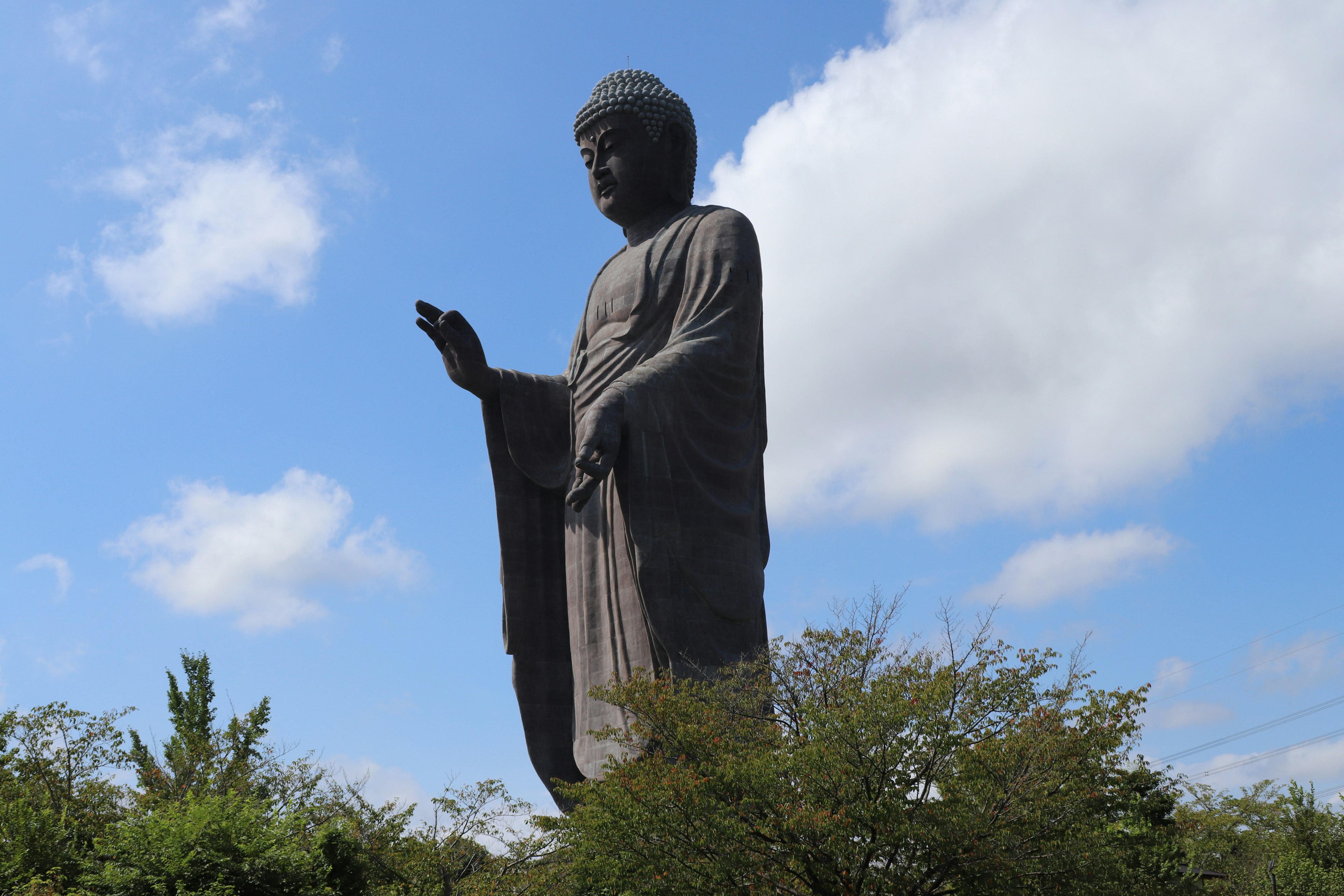 Gigantische Buddha-Statue steht unter einem blauen Himmel