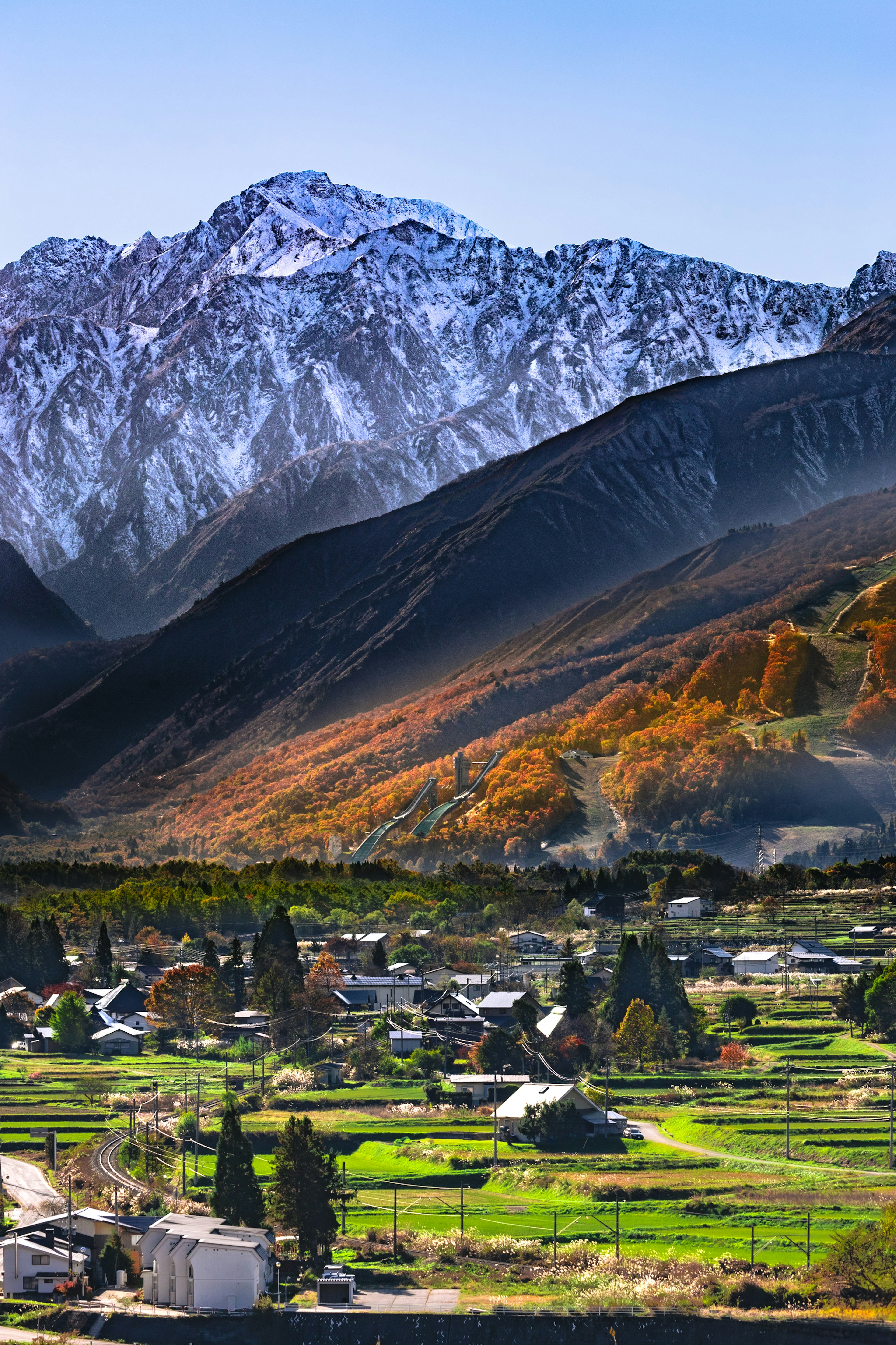 美しい山々と色とりどりの秋の木々に囲まれた村の風景