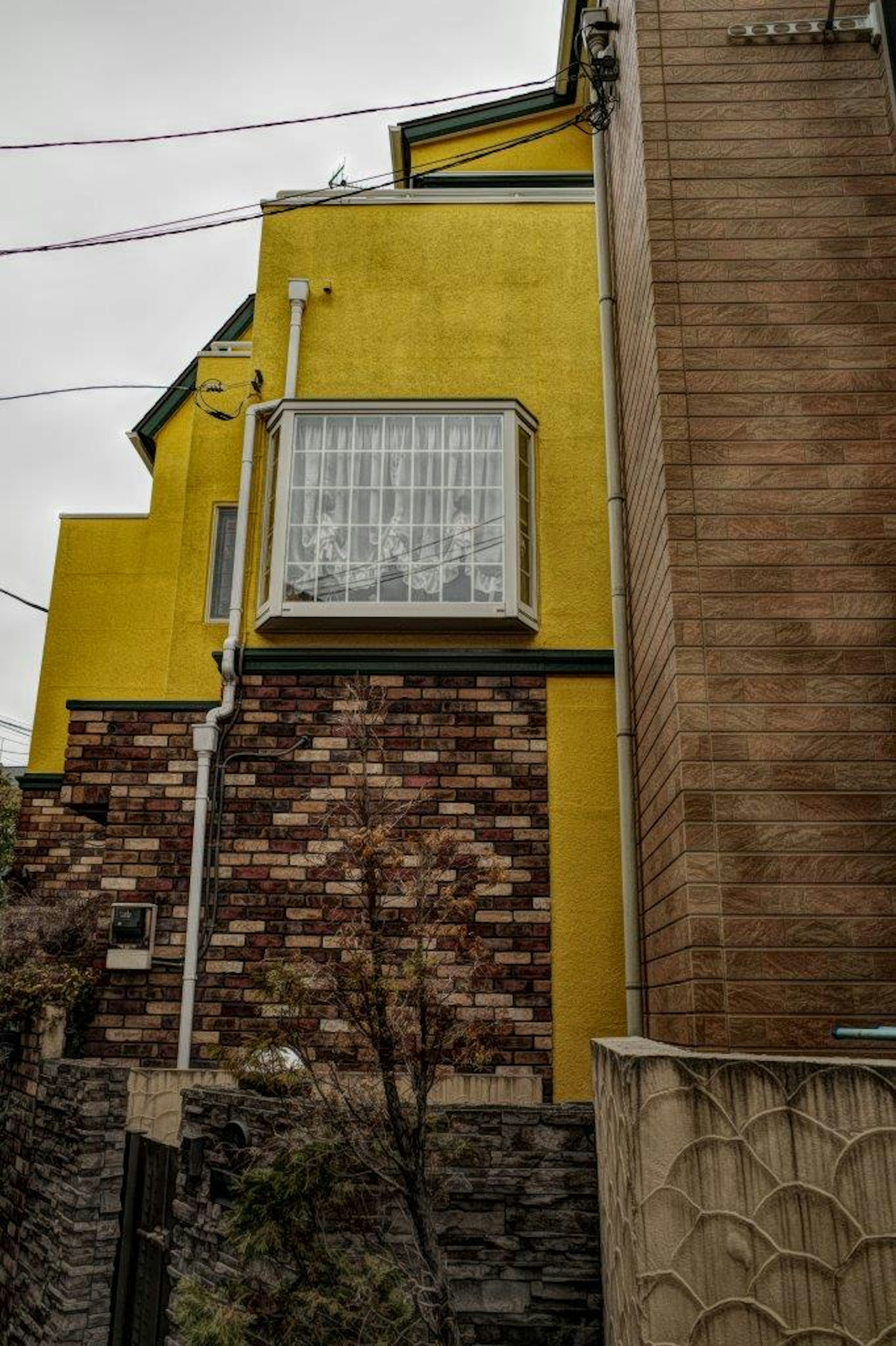 A house with a yellow wall and brick exterior