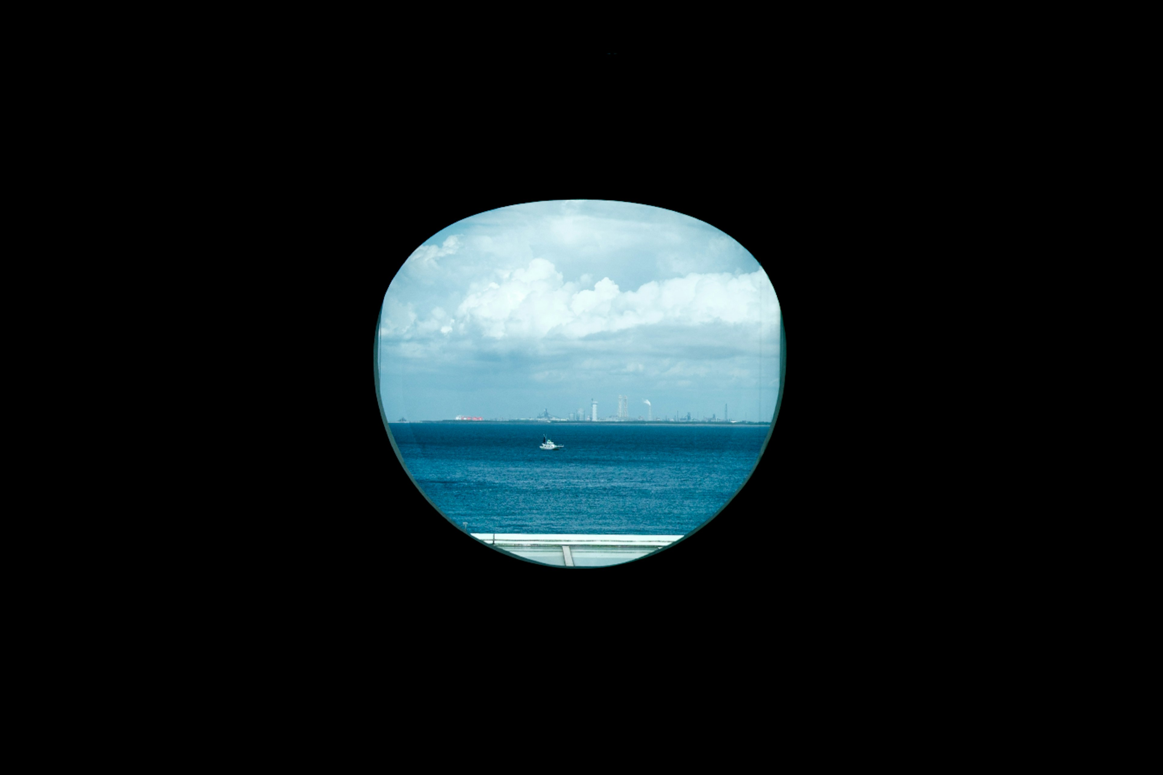 View of blue ocean and clouds through a round window