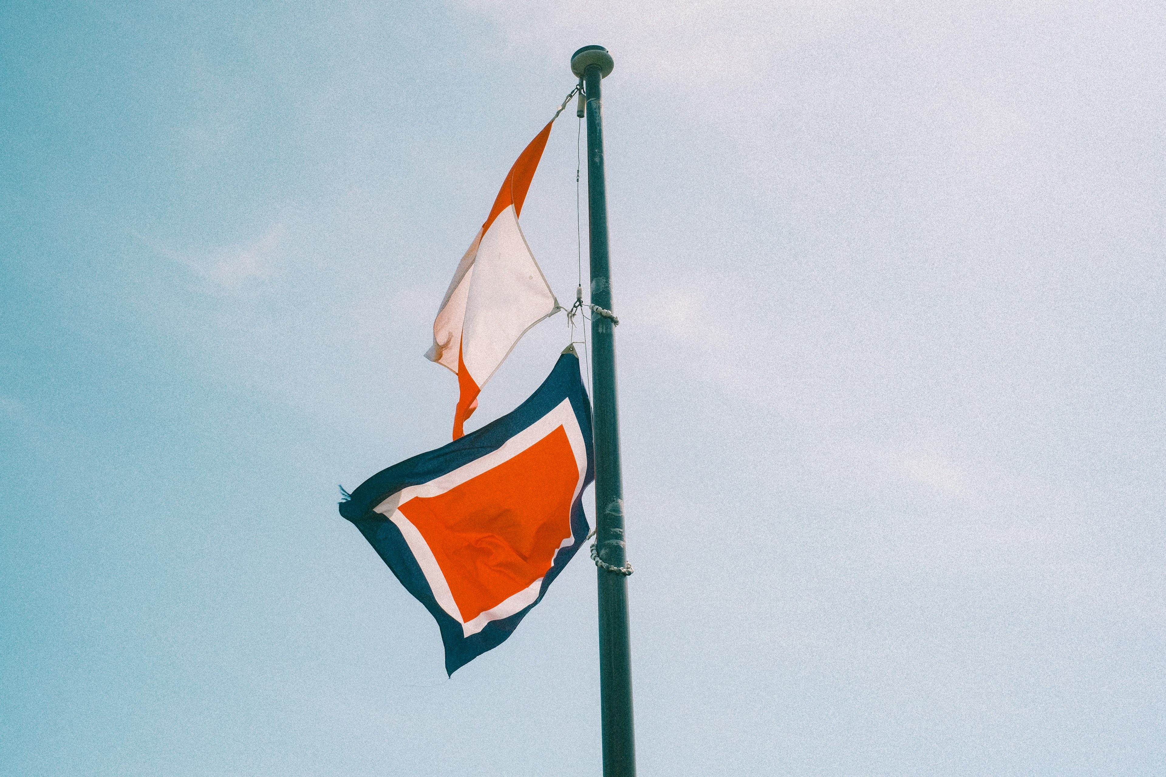 Dua bendera dipajang di tiang di bawah langit biru