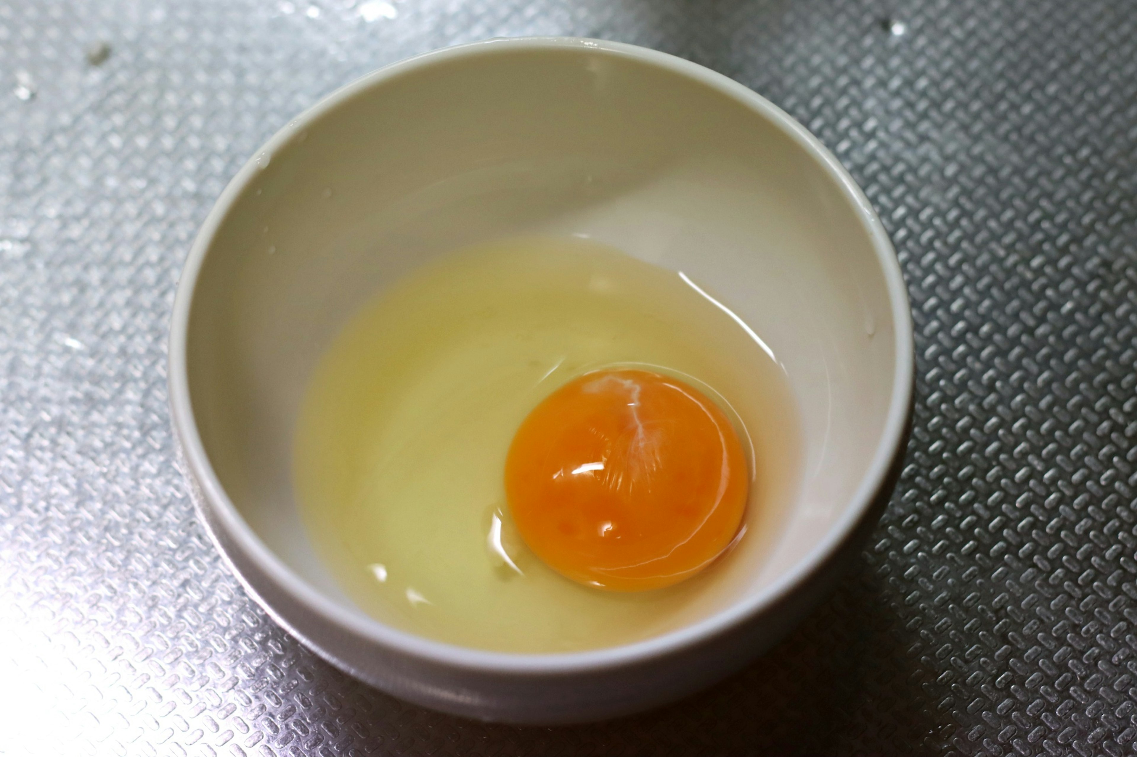 Egg yolk and clear egg white in a white bowl