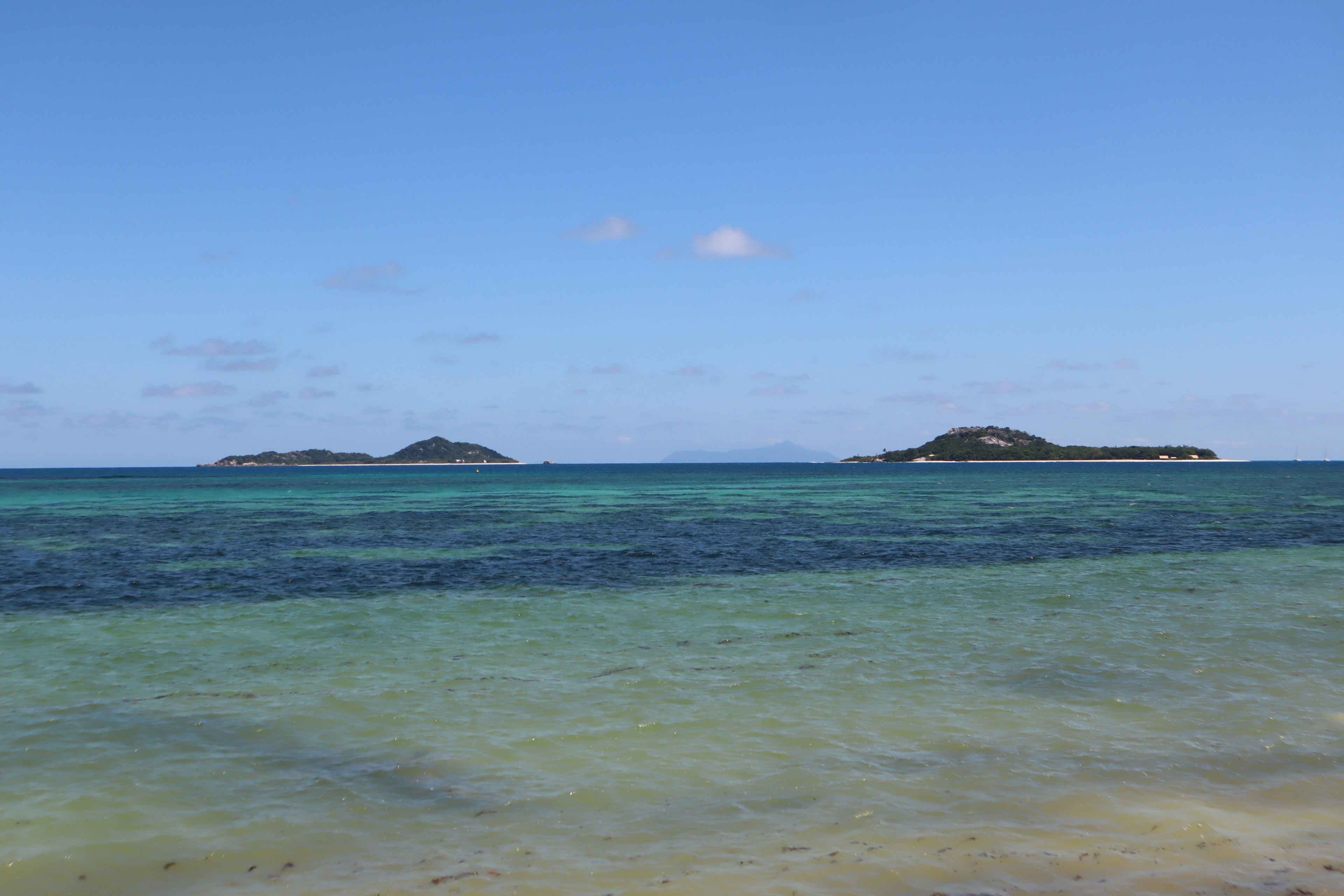 青い海と空の間に小さな島々が見える美しいビーチの風景