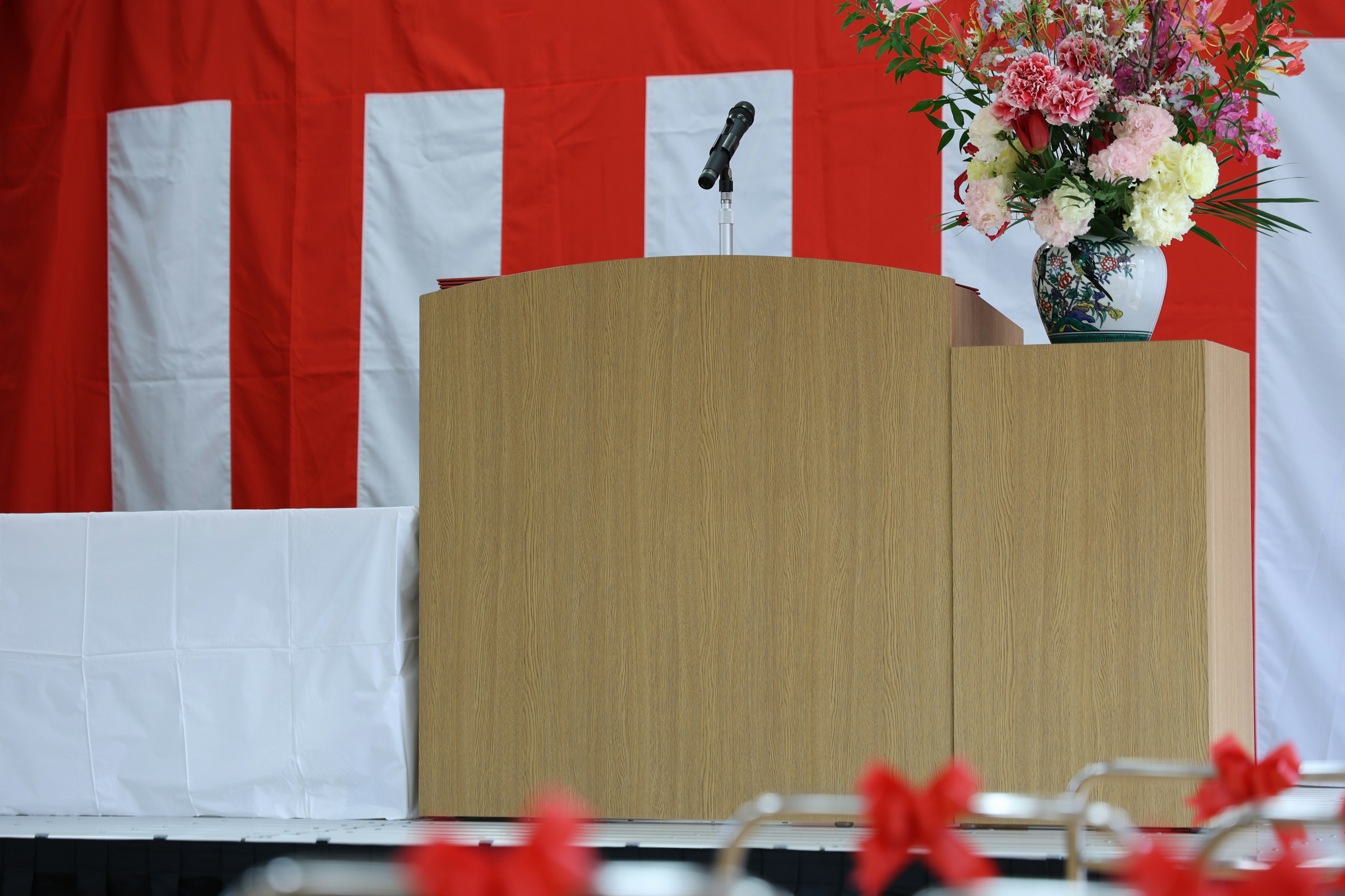 Stage with red background featuring white stripes and a vase of flowers