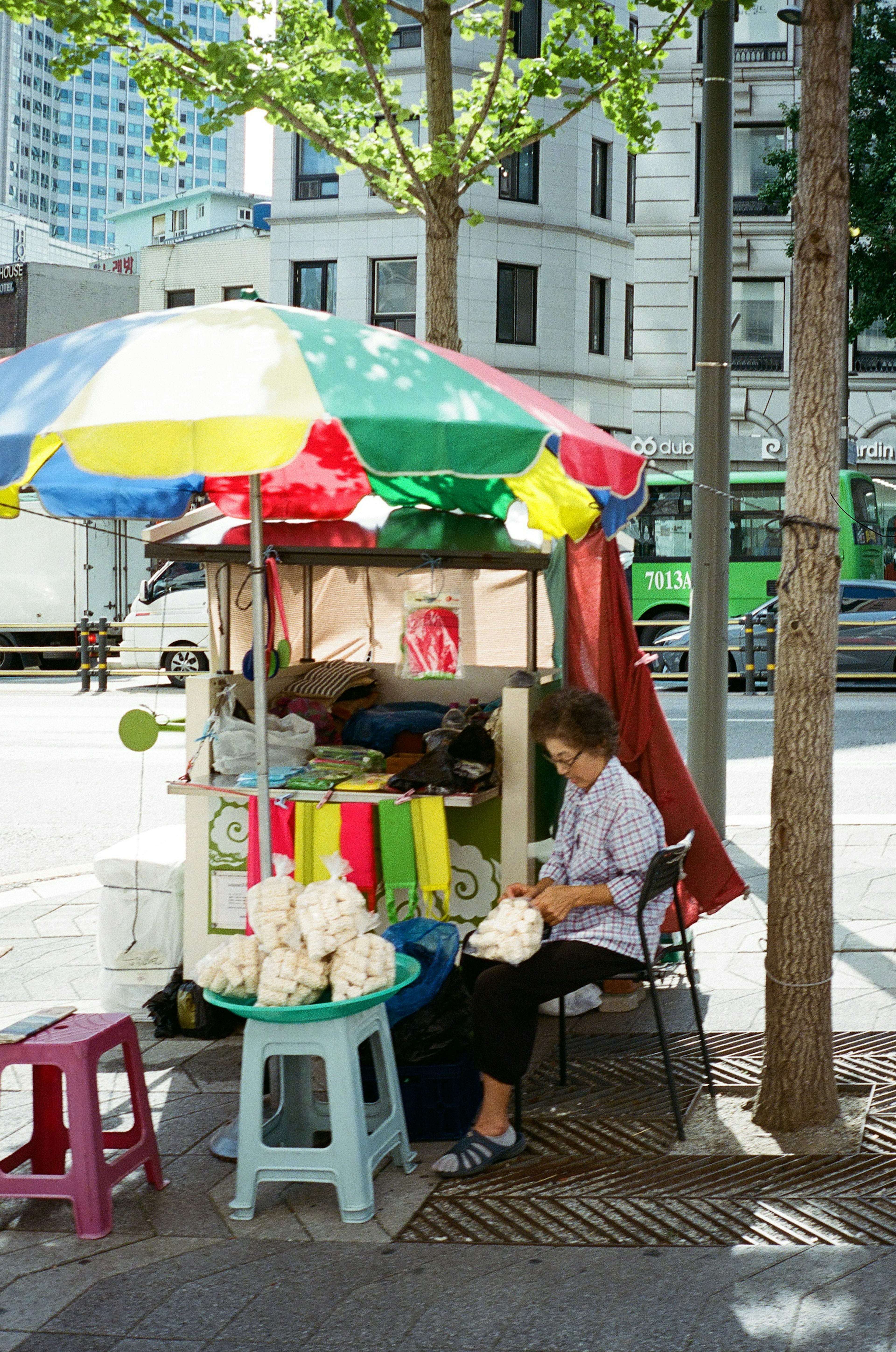 Un vendeur sous un parapluie coloré arrangeant des produits dans un stand de rue