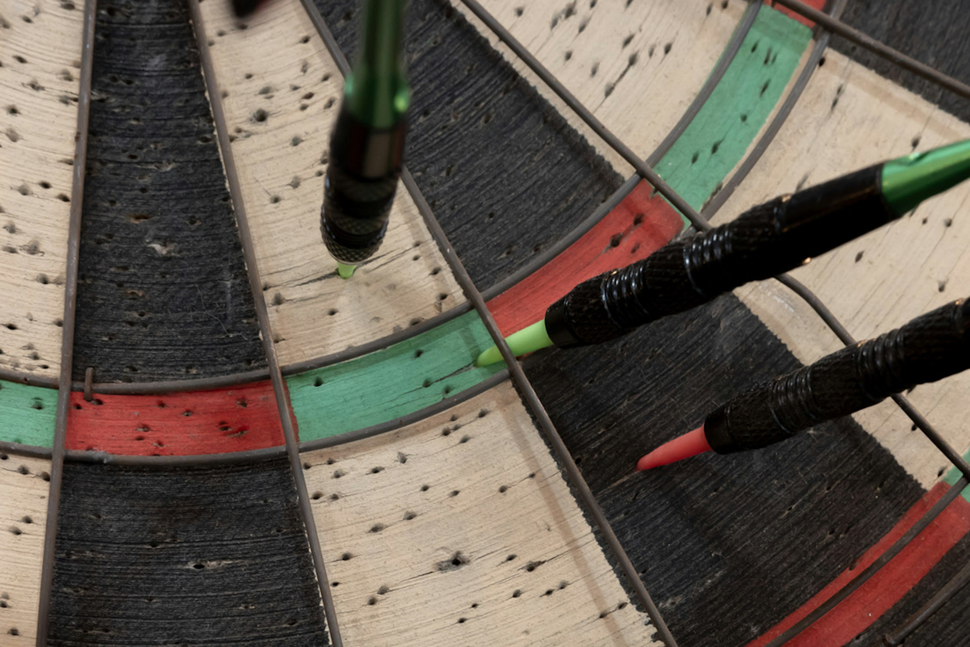 Close-up of darts embedded in a dartboard with green and red sections