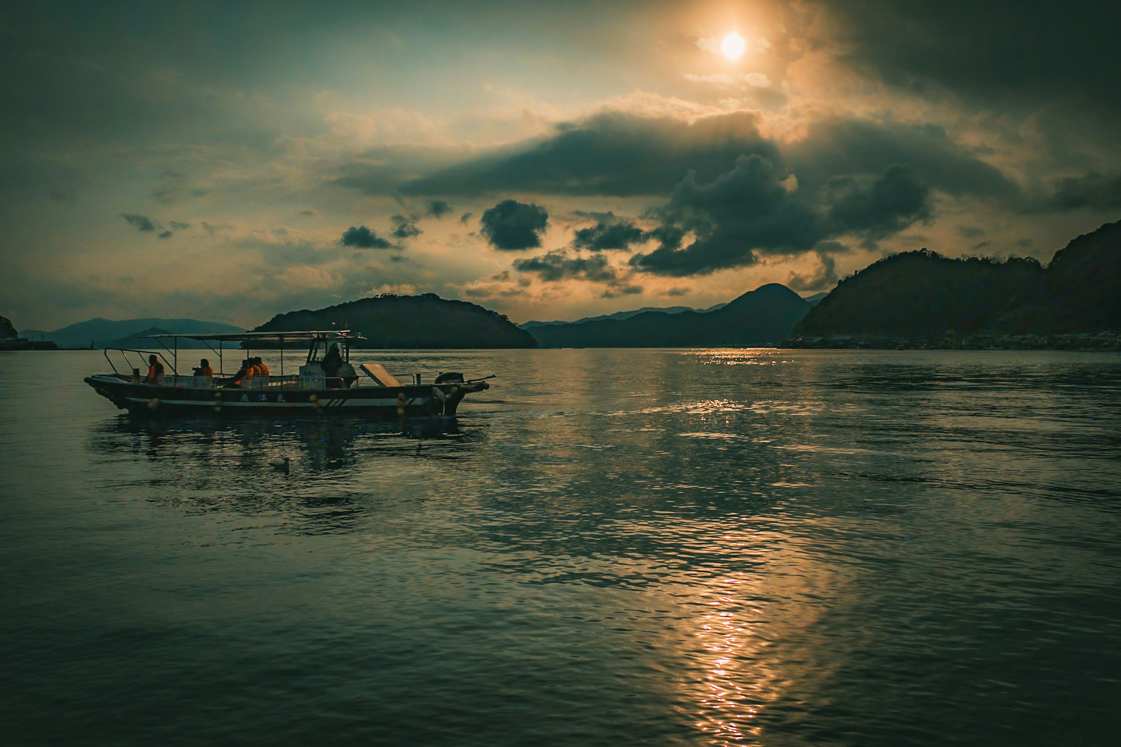 静かな水面に浮かぶボートと夕日が照らす風景