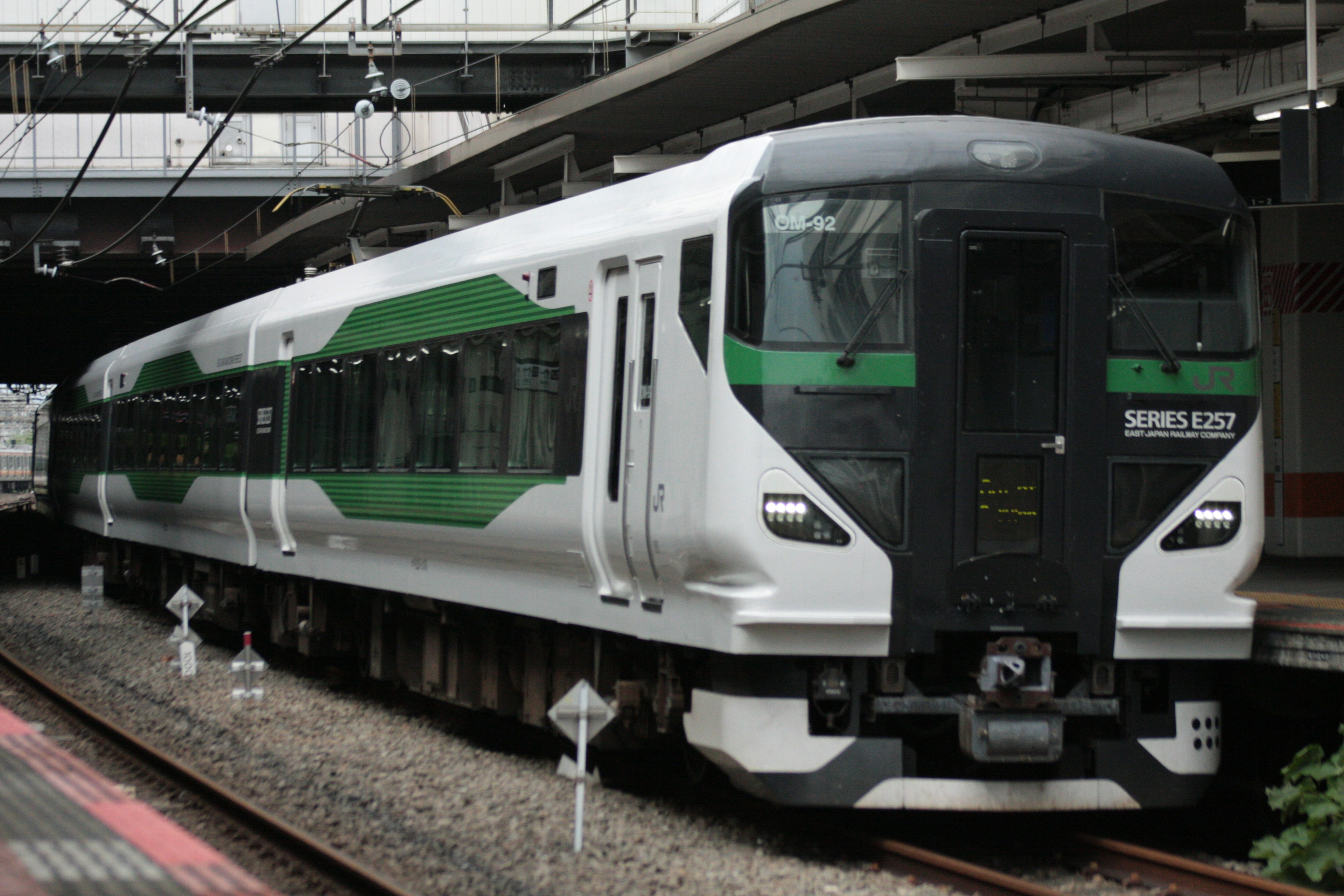 Kereta putih dengan garis hijau diparkir di stasiun