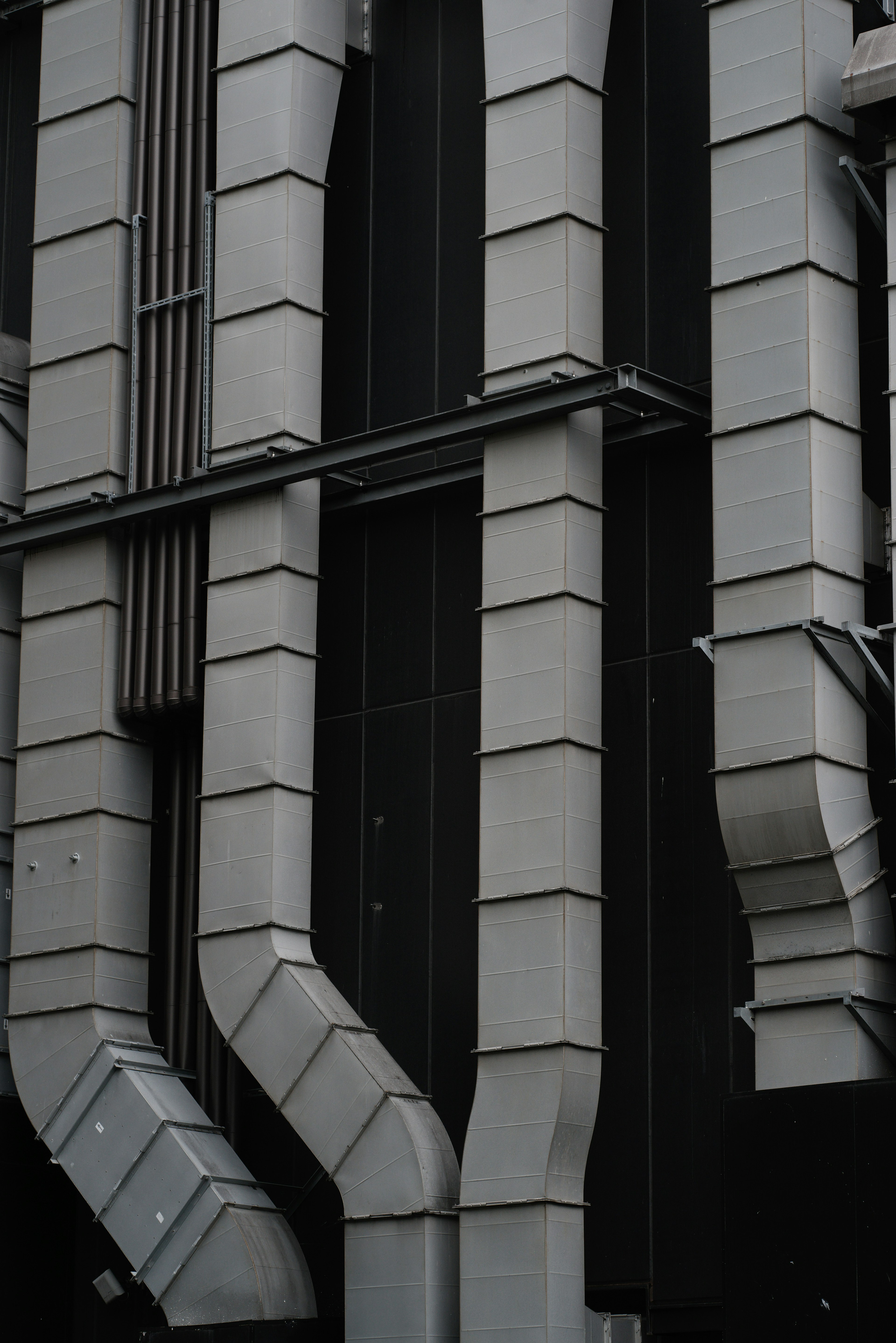 Tuberías metálicas y ranuras verticales en una fachada de edificio negro