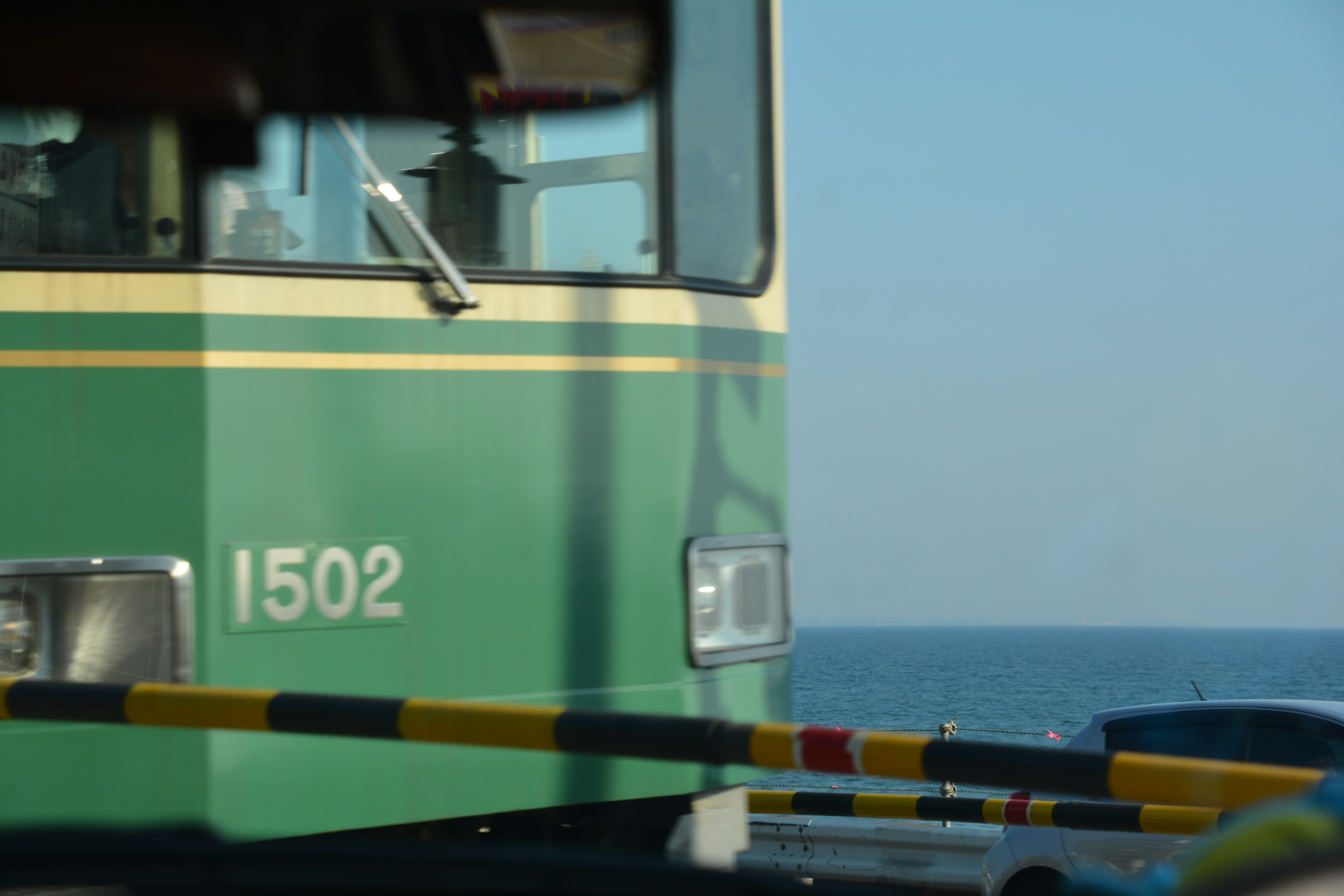 海を背景にした緑色の電車の前面部分