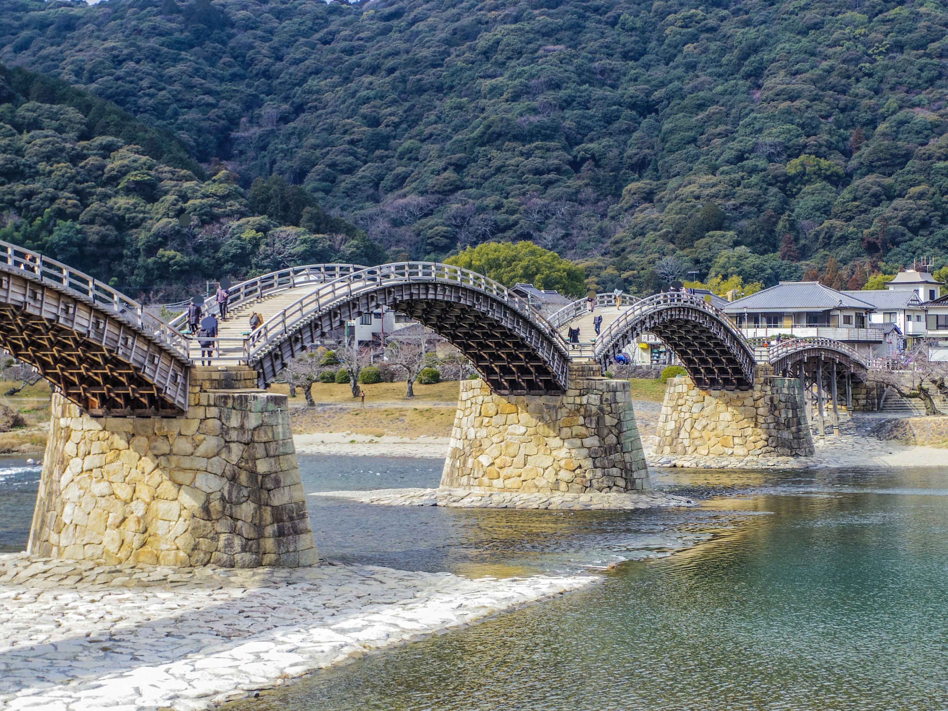 Beautiful wooden bridge spanning a river with distinctive arches and mountains in the background