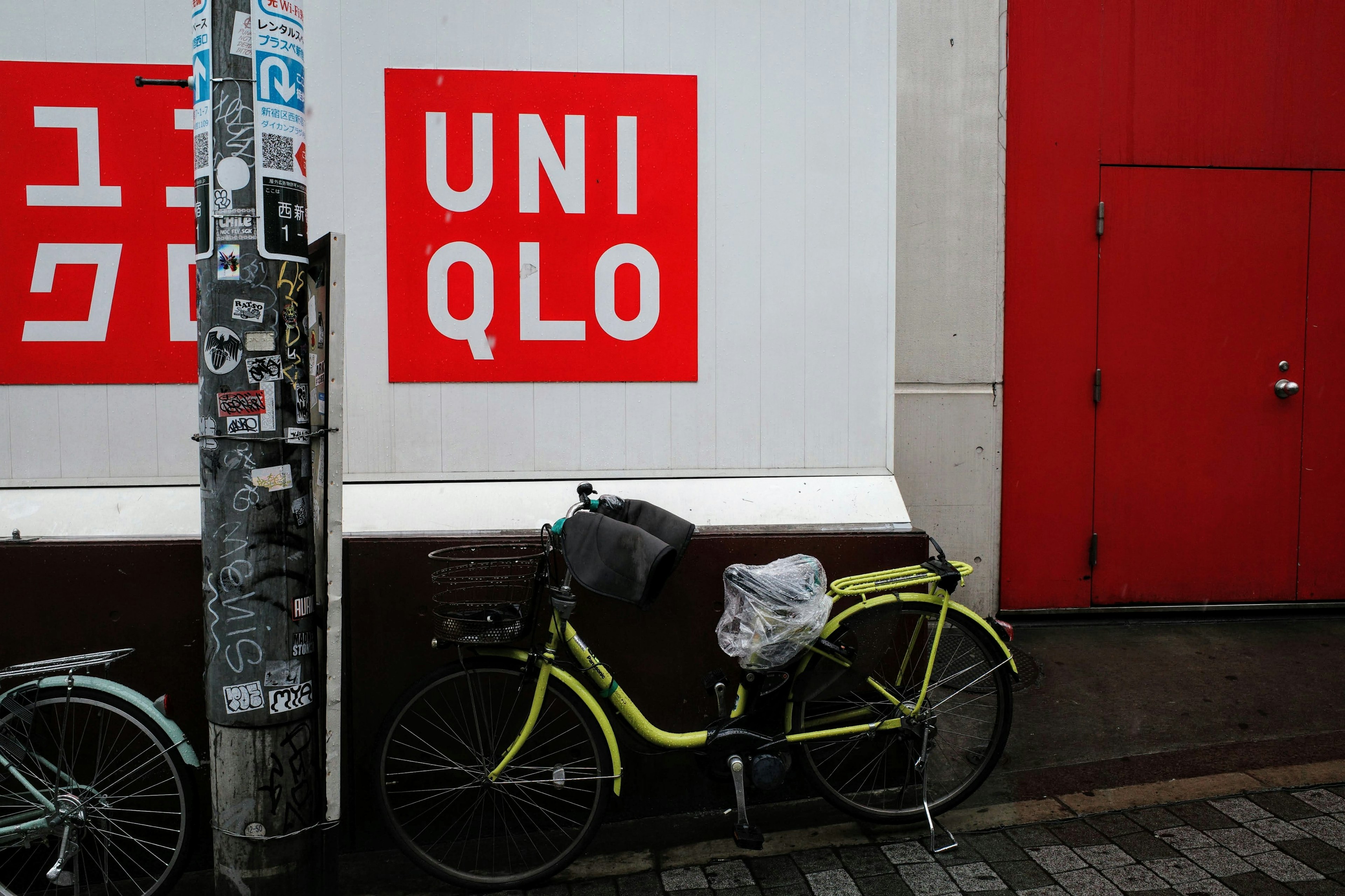 ユニクロの店舗の赤い看板と自転車が映る街角の風景