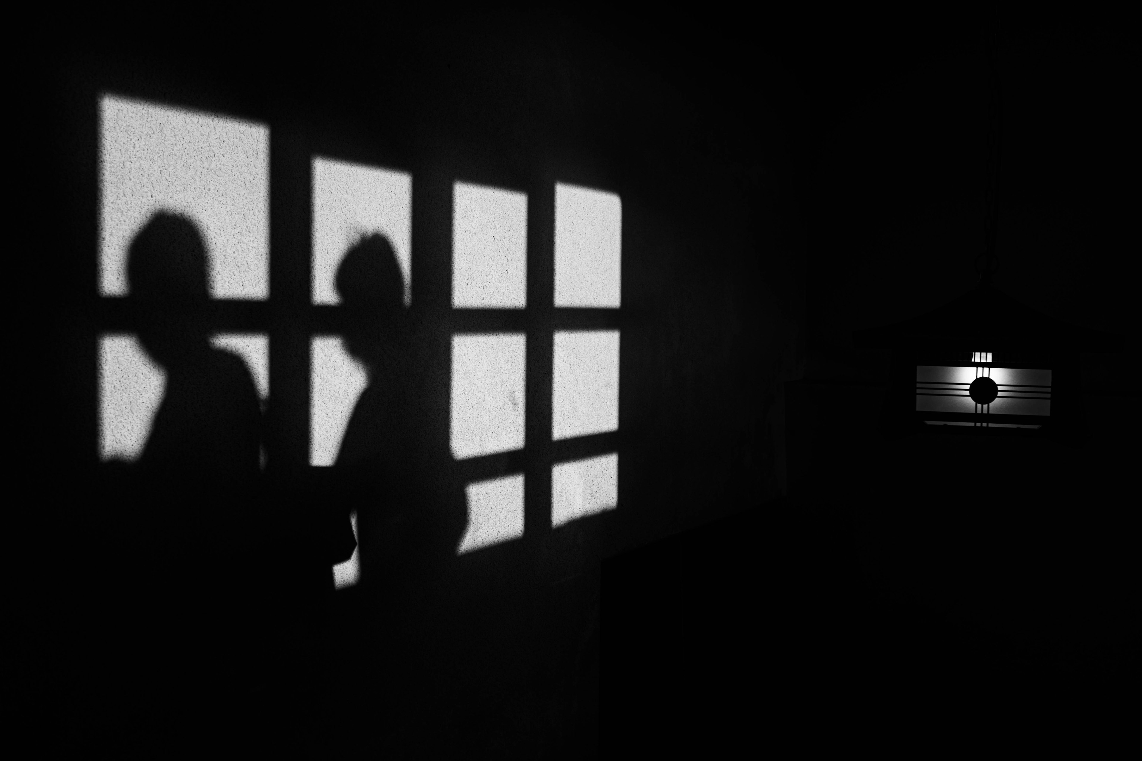 Silhouettes of people against a dark background with window shadows