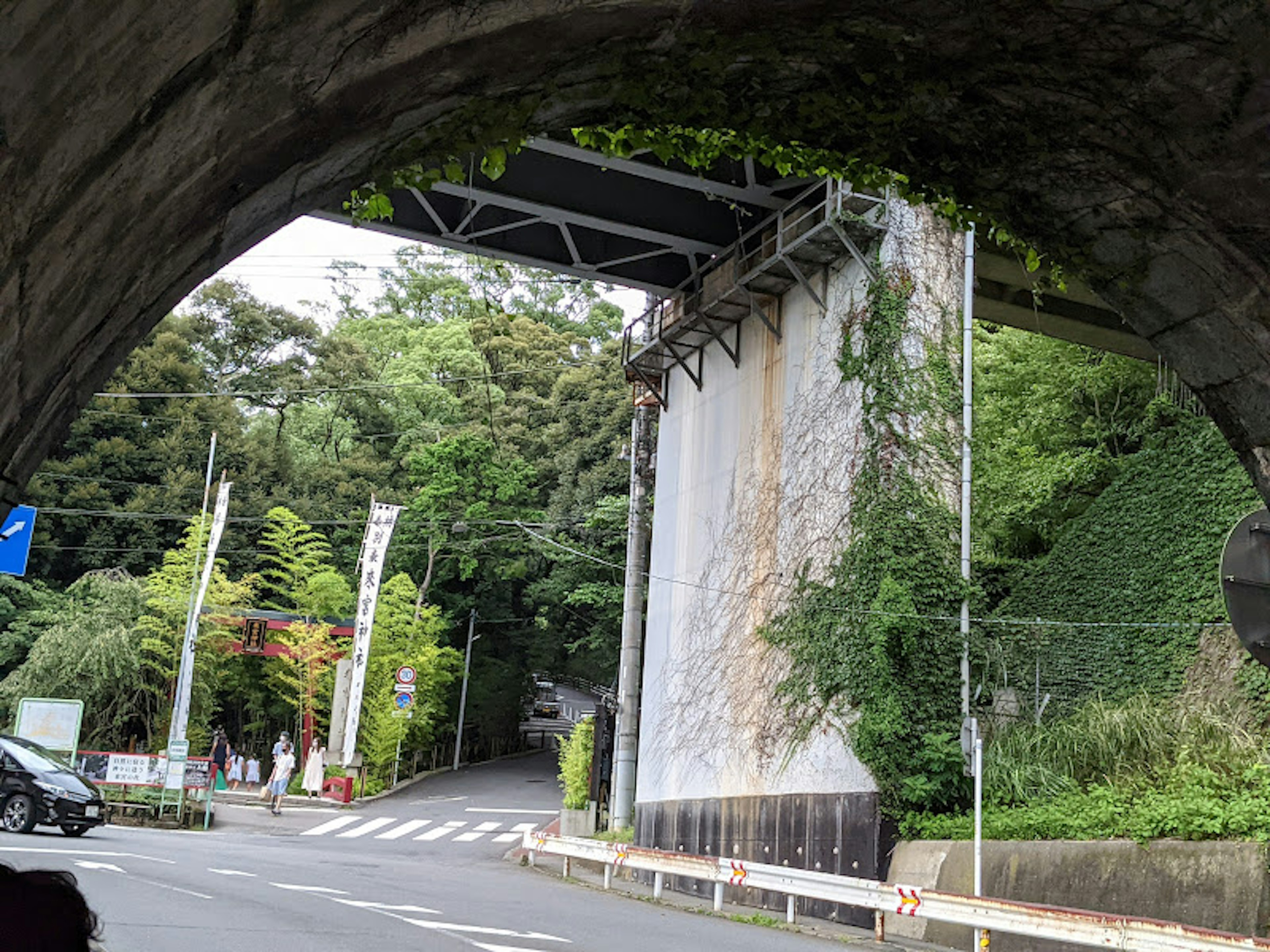 A view from under a tunnel arch showing a lush green road and wall