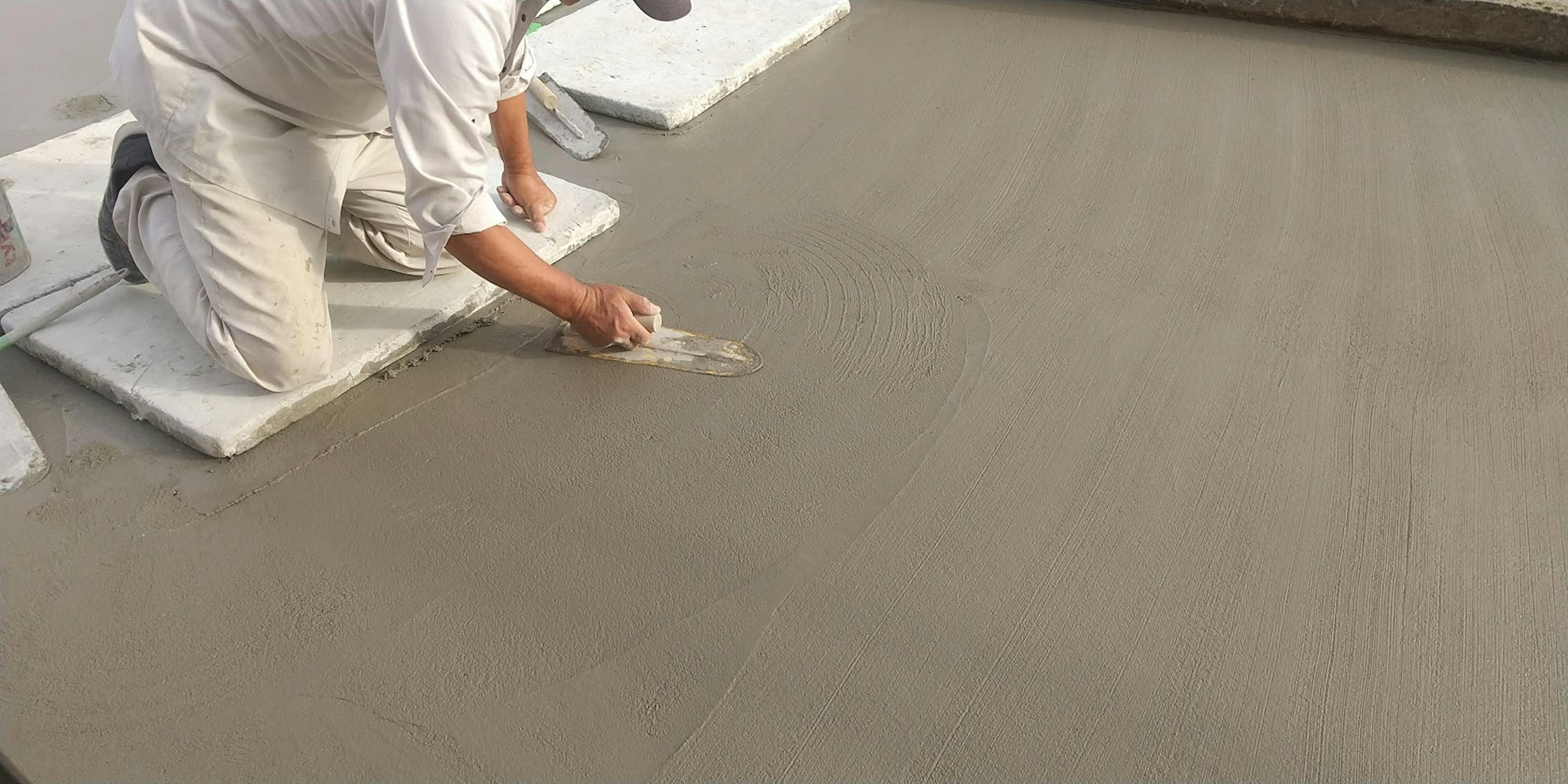 Worker leveling concrete surface with trowel