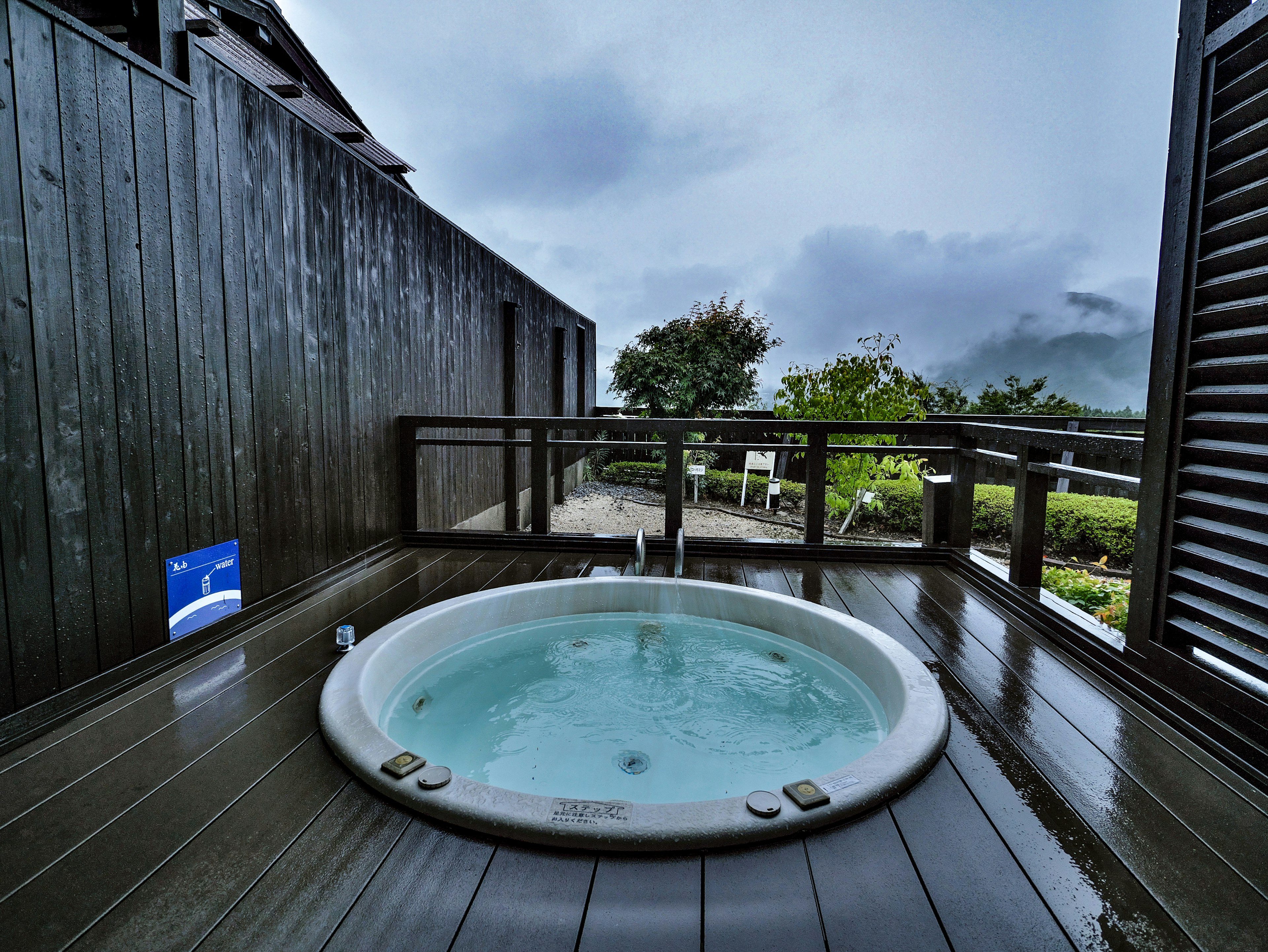 Jacuzzi all'aperto su una terrazza in legno con vegetazione lussureggiante