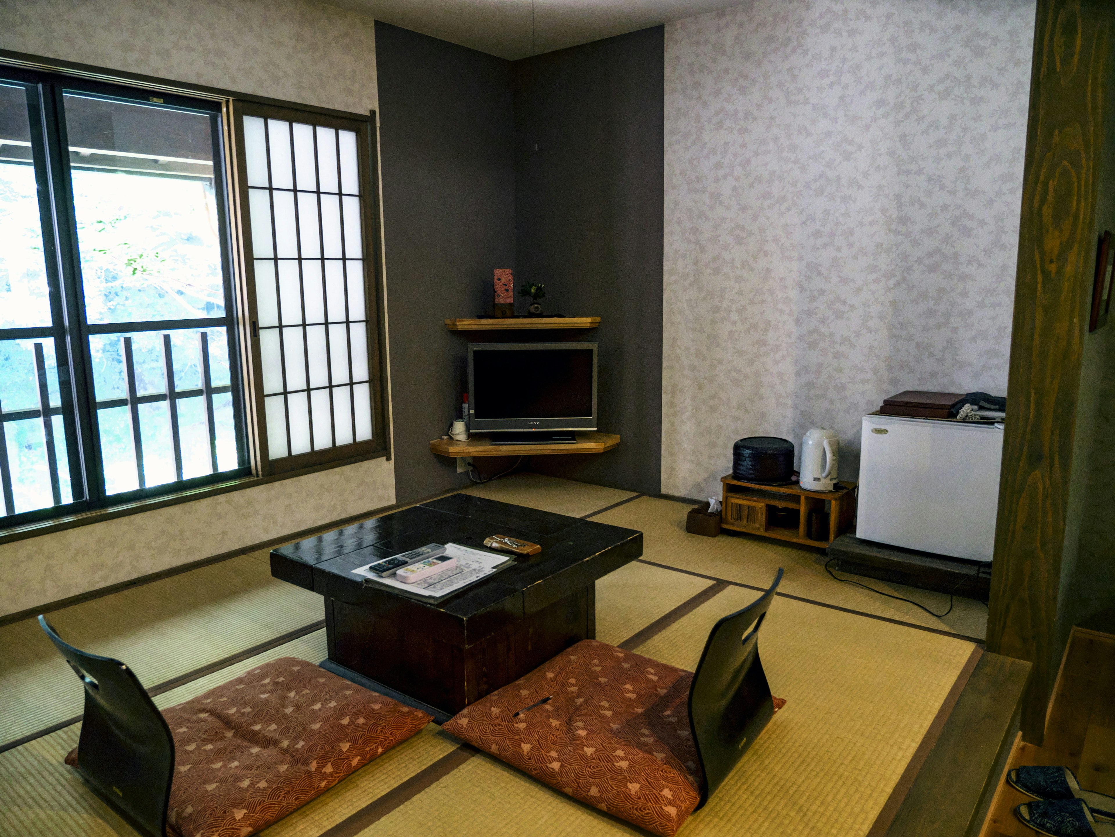 Interior de habitación japonesa tradicional con suelo de tatami mesa baja y cojines con televisor