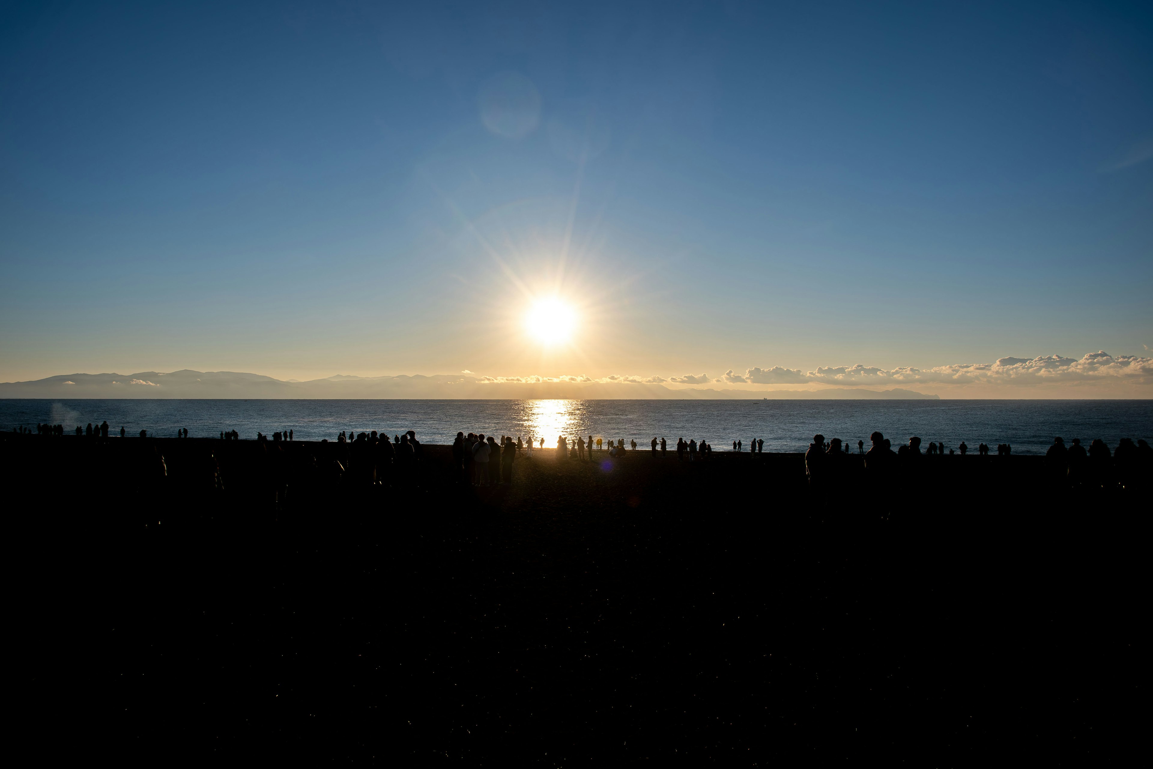 Atardecer sobre el océano con siluetas de personas