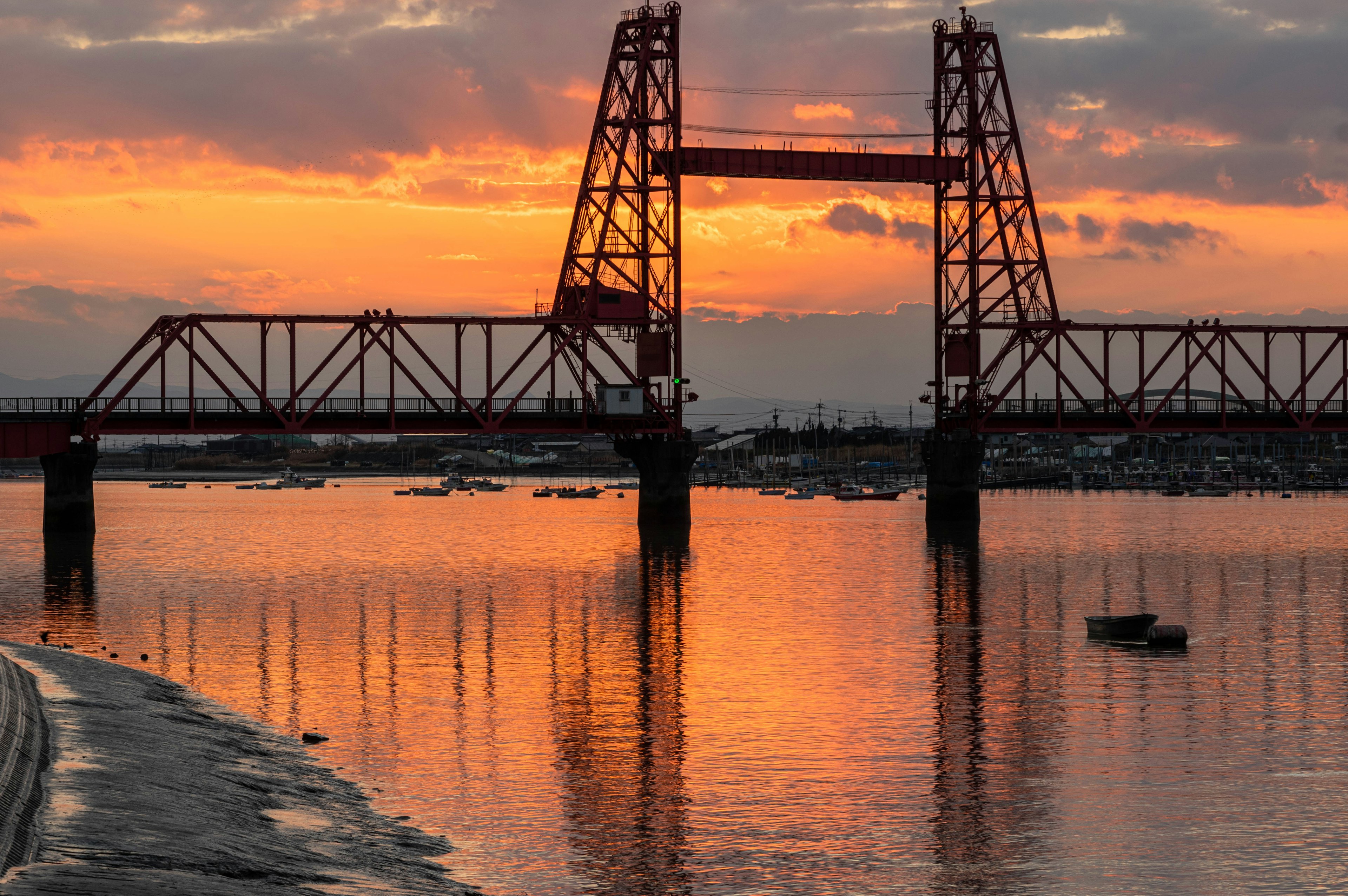 Eine bei Sonnenuntergang beleuchtete Eisenbrücke, die sich in ruhigen Gewässern spiegelt