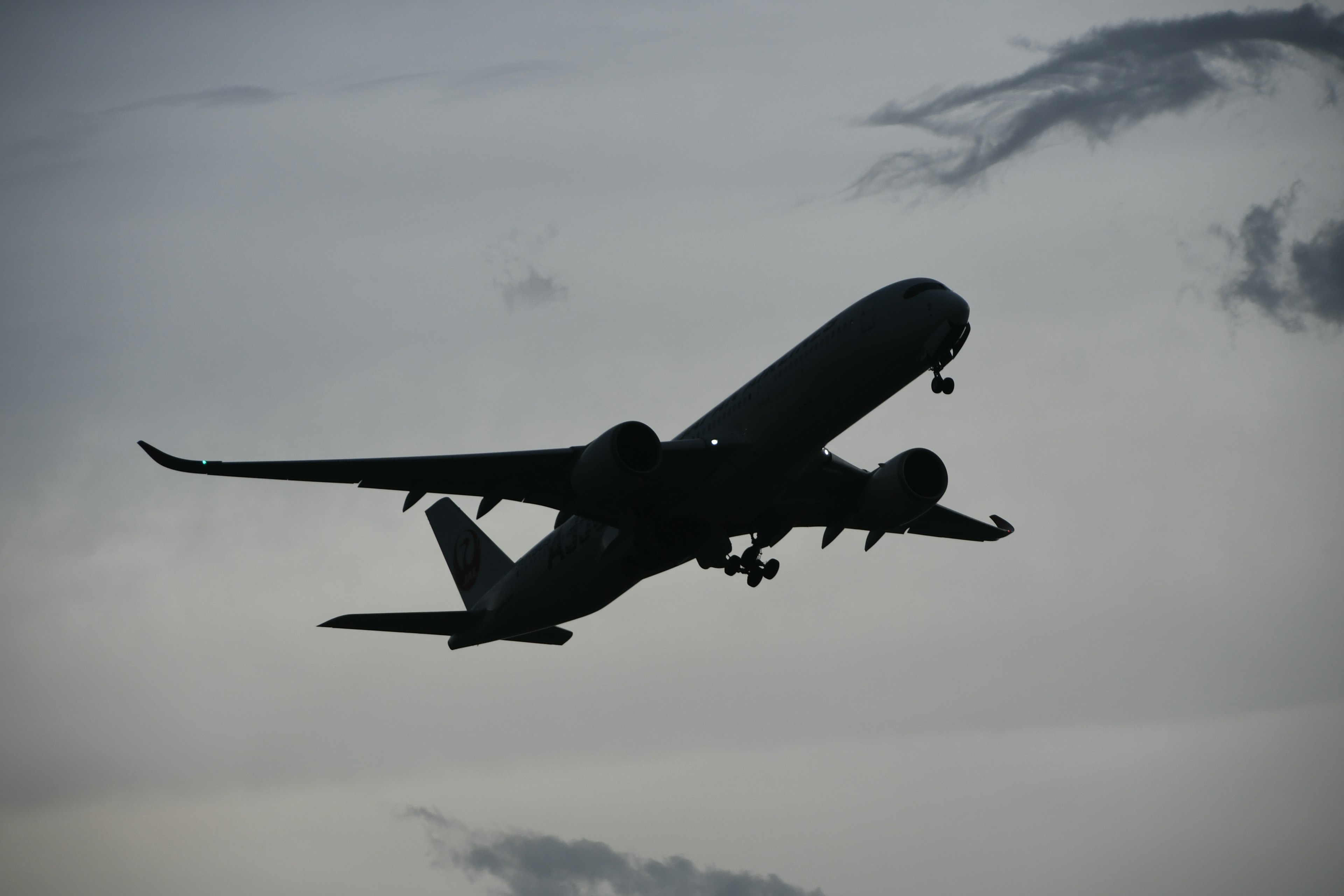 Silhouette d'un avion volant contre un ciel nuageux