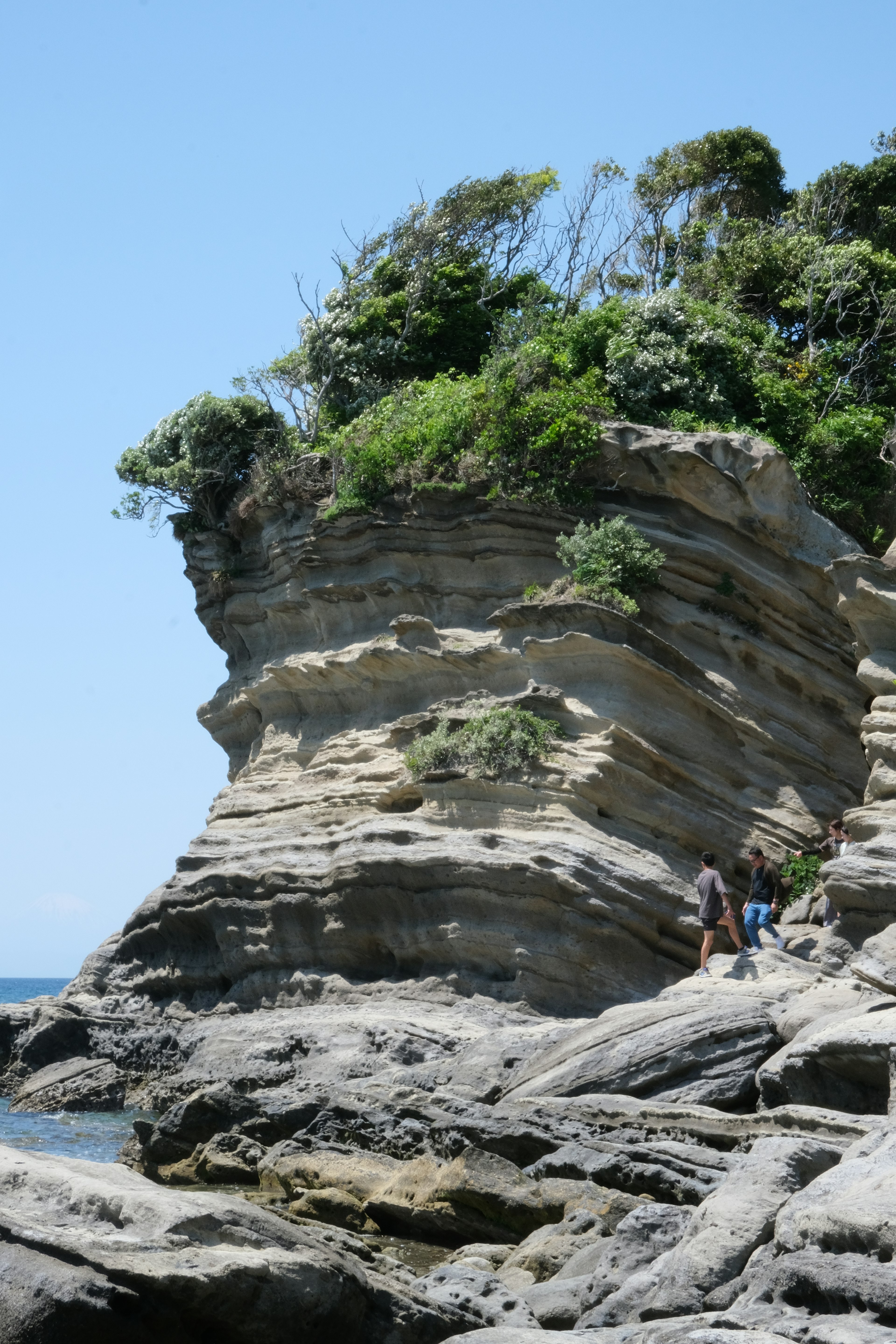 Coastal rock formation with people walking nearby