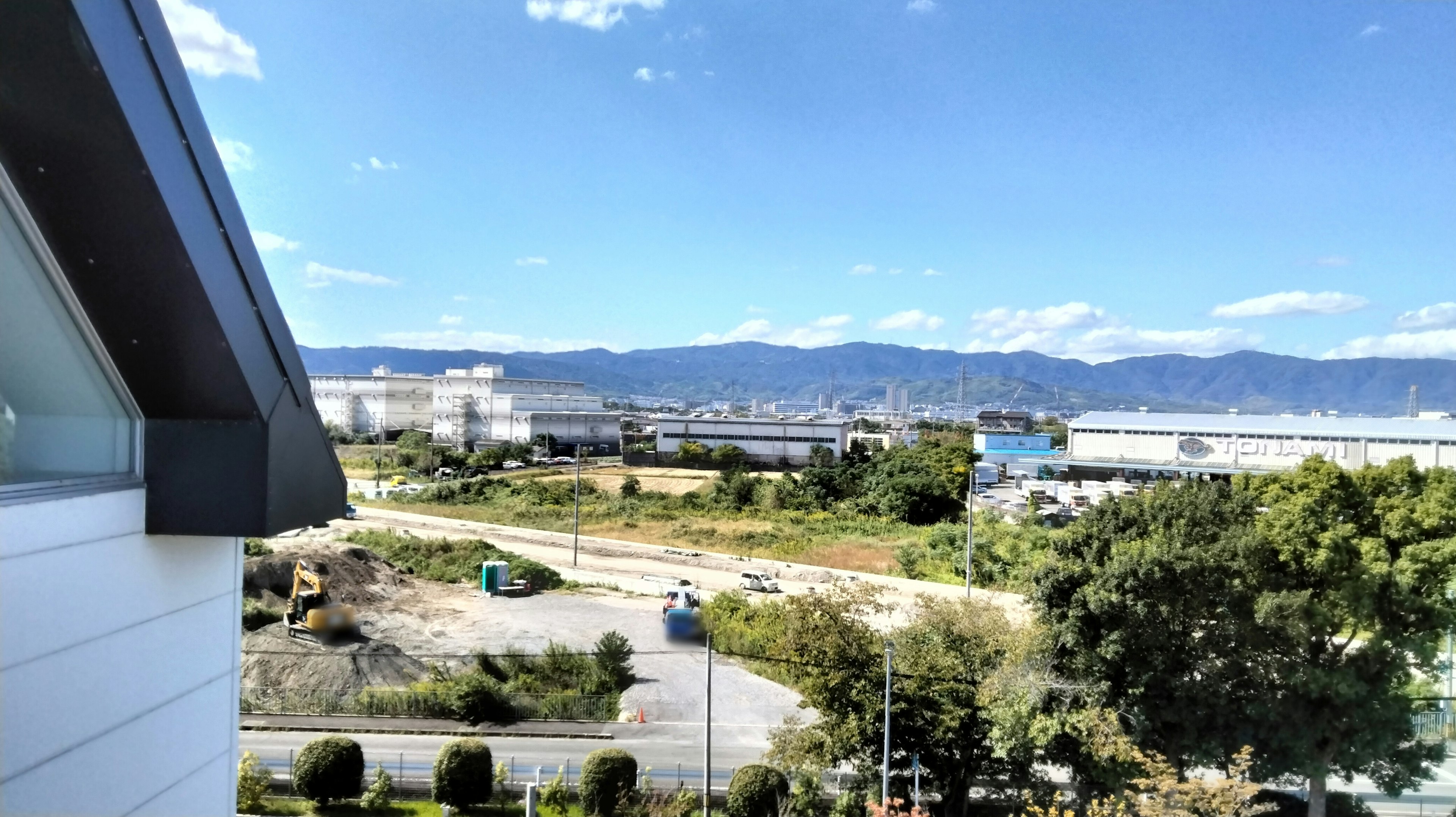 Landscape featuring blue sky and mountains with construction site and vehicles visible