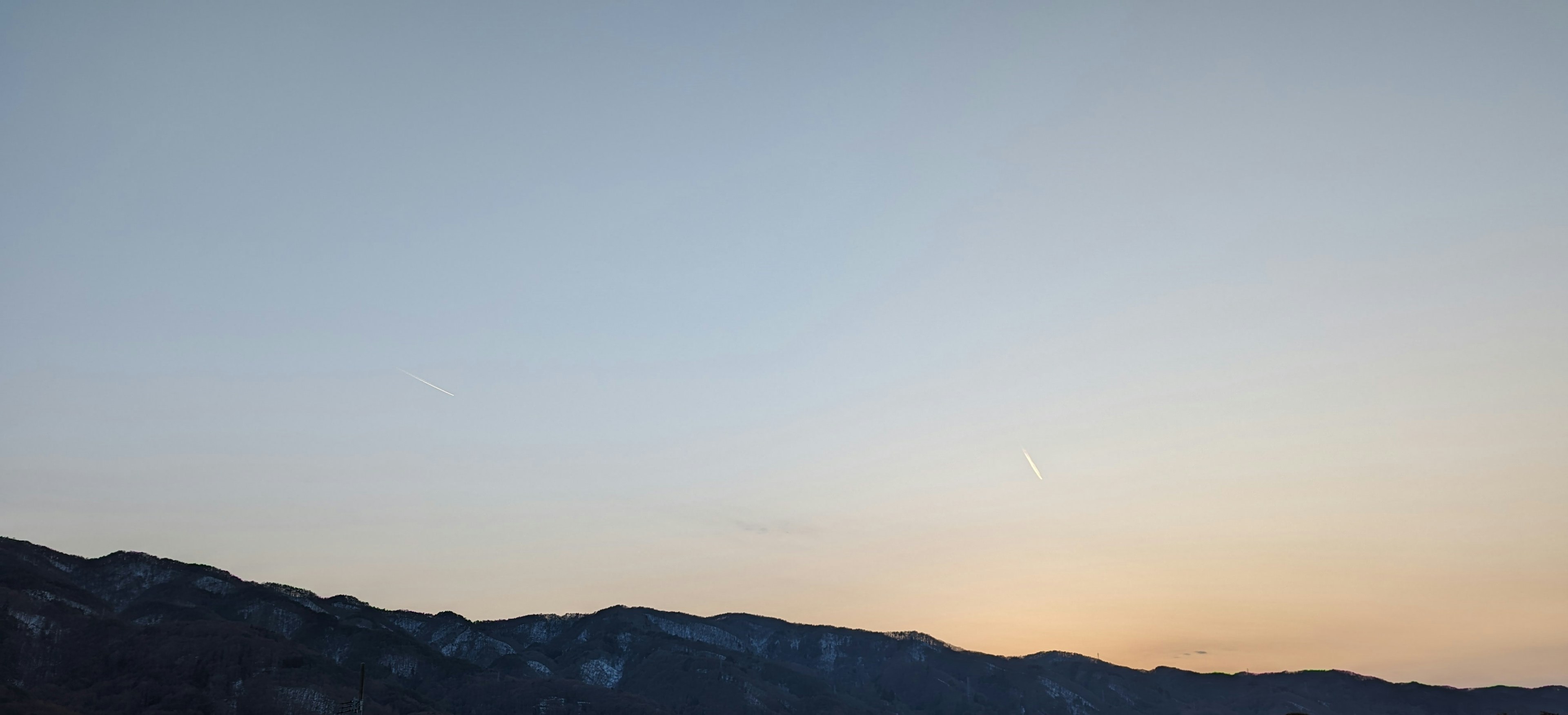 Silhouette of mountains against a pale orange sky