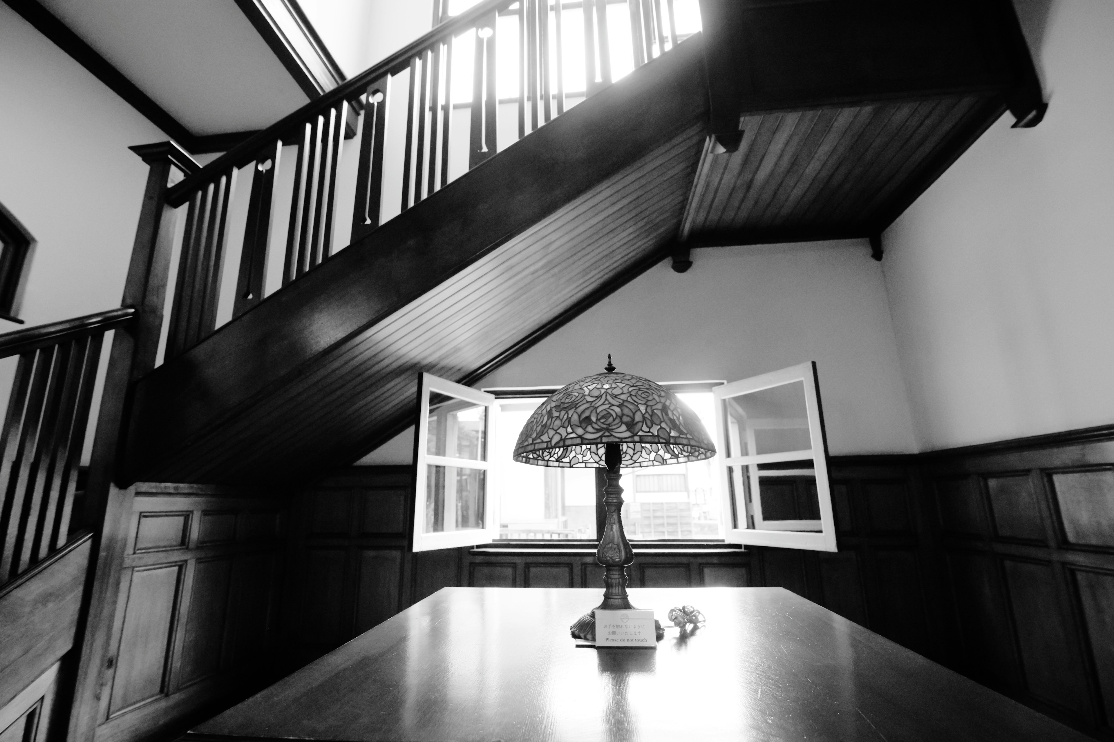 Interior of a room featuring a staircase and window with a lamp on the table