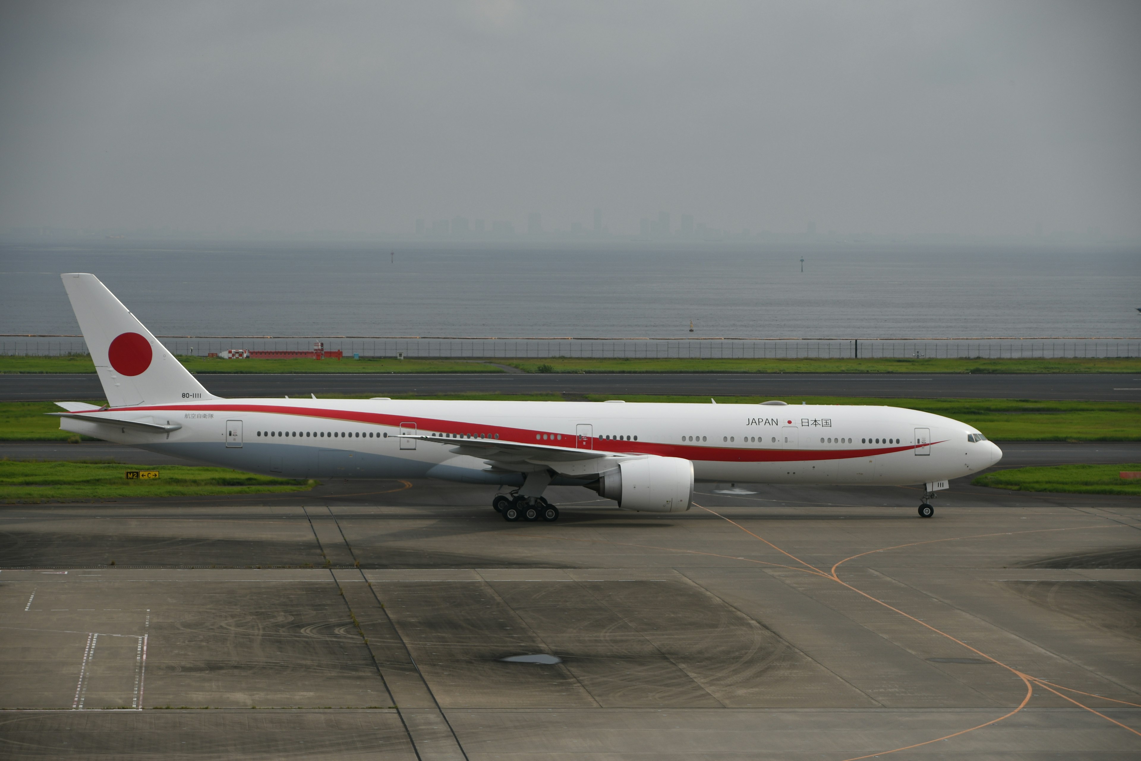 Japanese airplane on the runway with red and white stripes