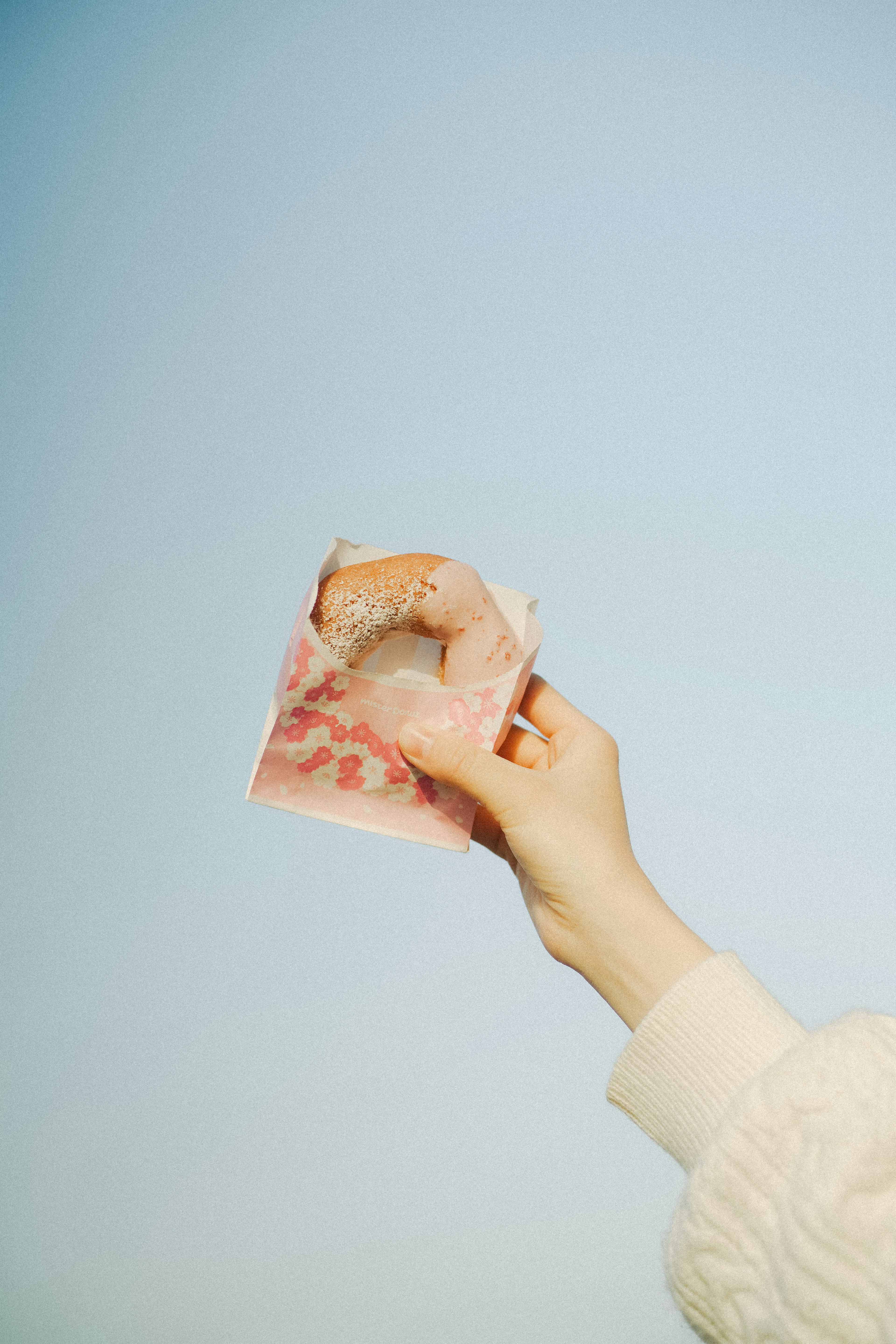 Hand holding a banknote against a clear blue sky