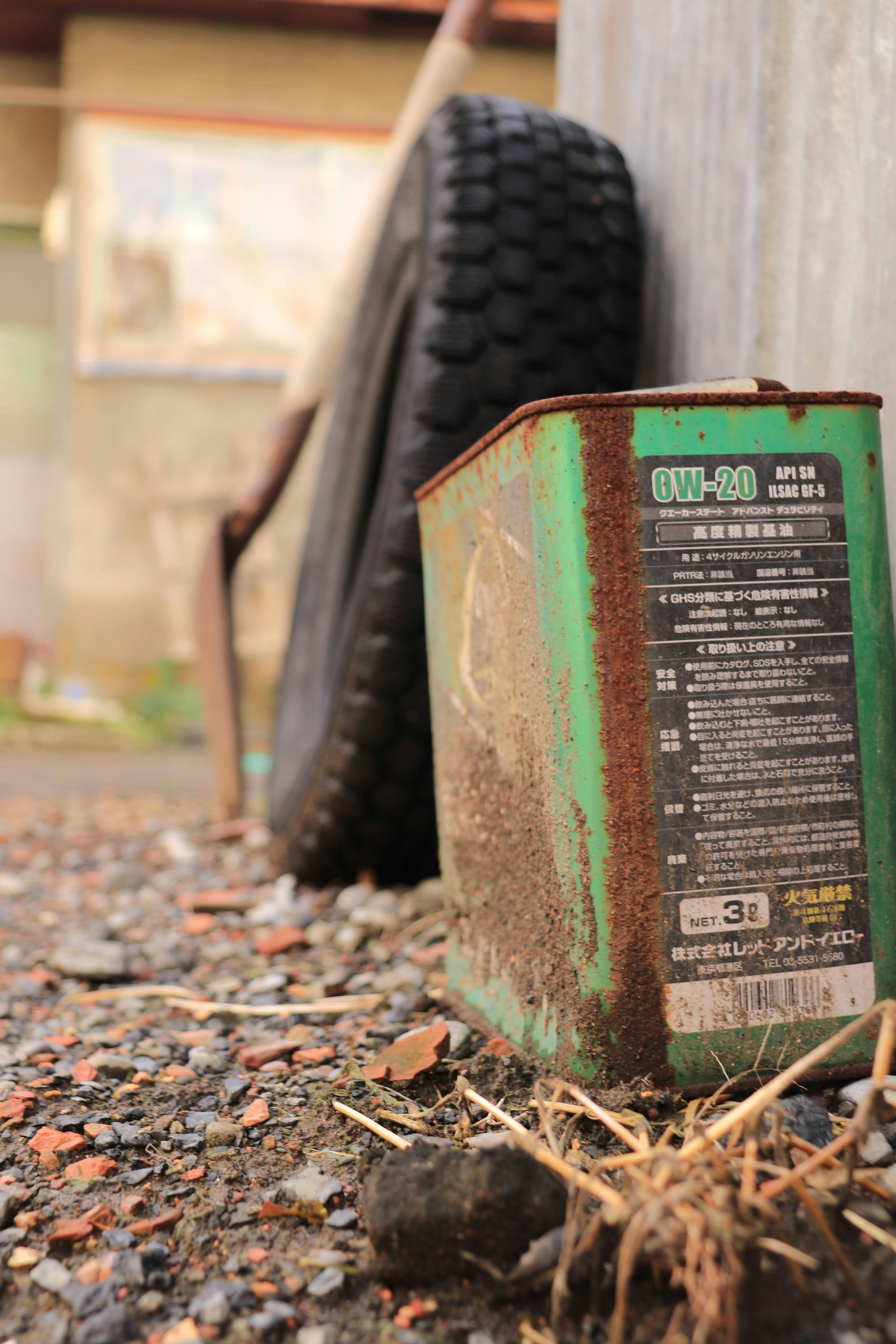 Rusty green can and old tire in an outdoor setting