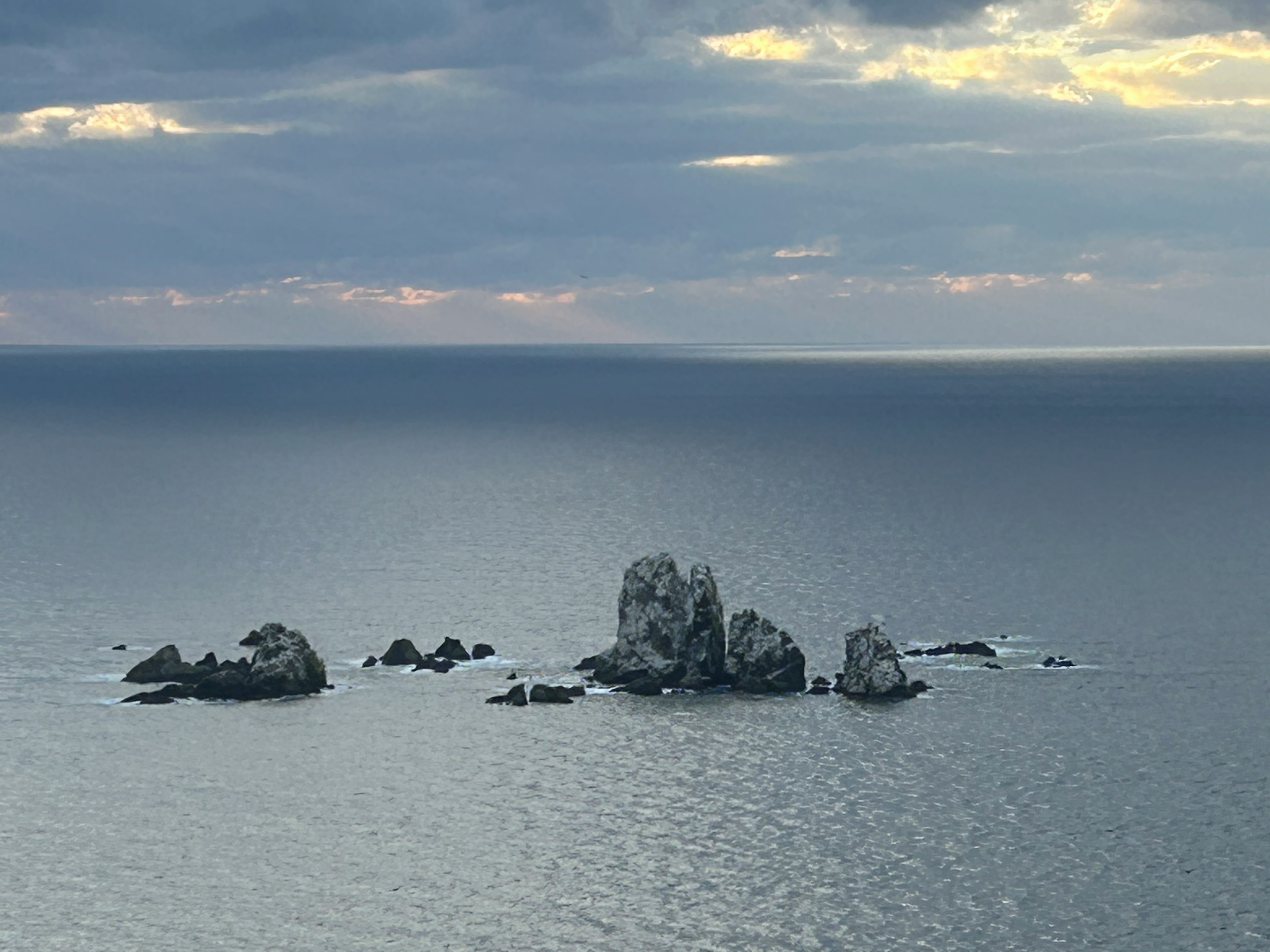 Serene sea with rocky outcrops and cloudy sky