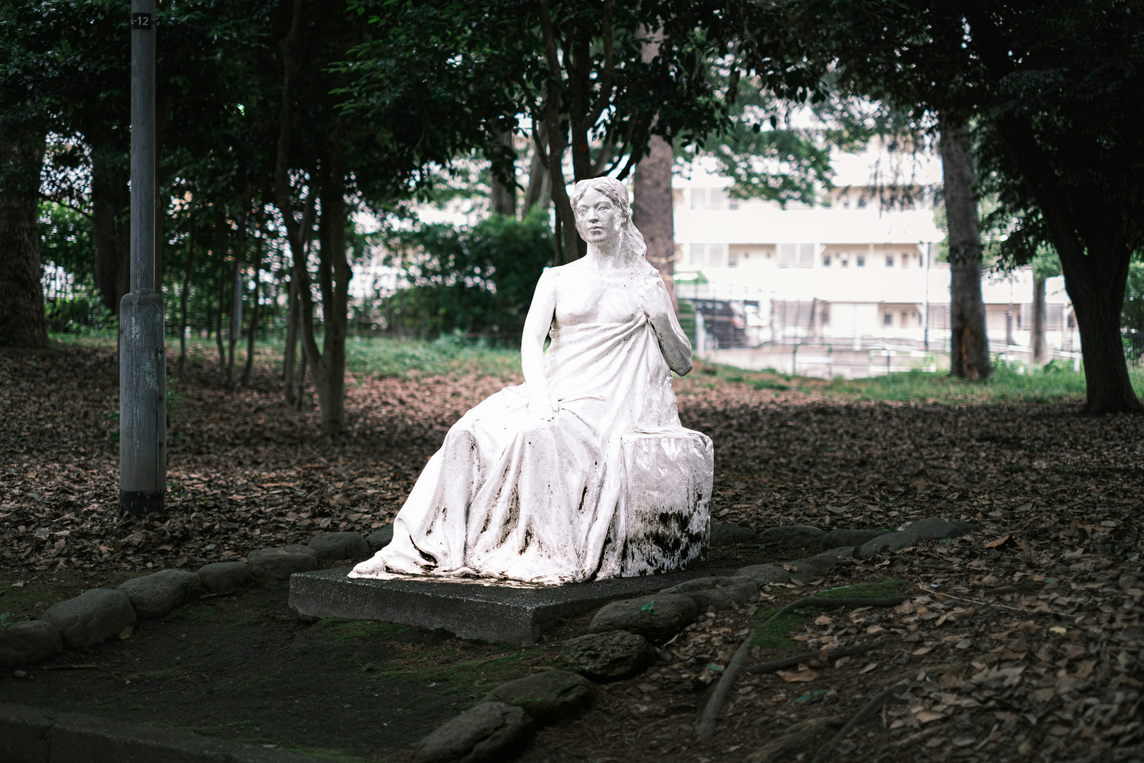 Une statue blanche assise dans un parc entourée d'arbres verts