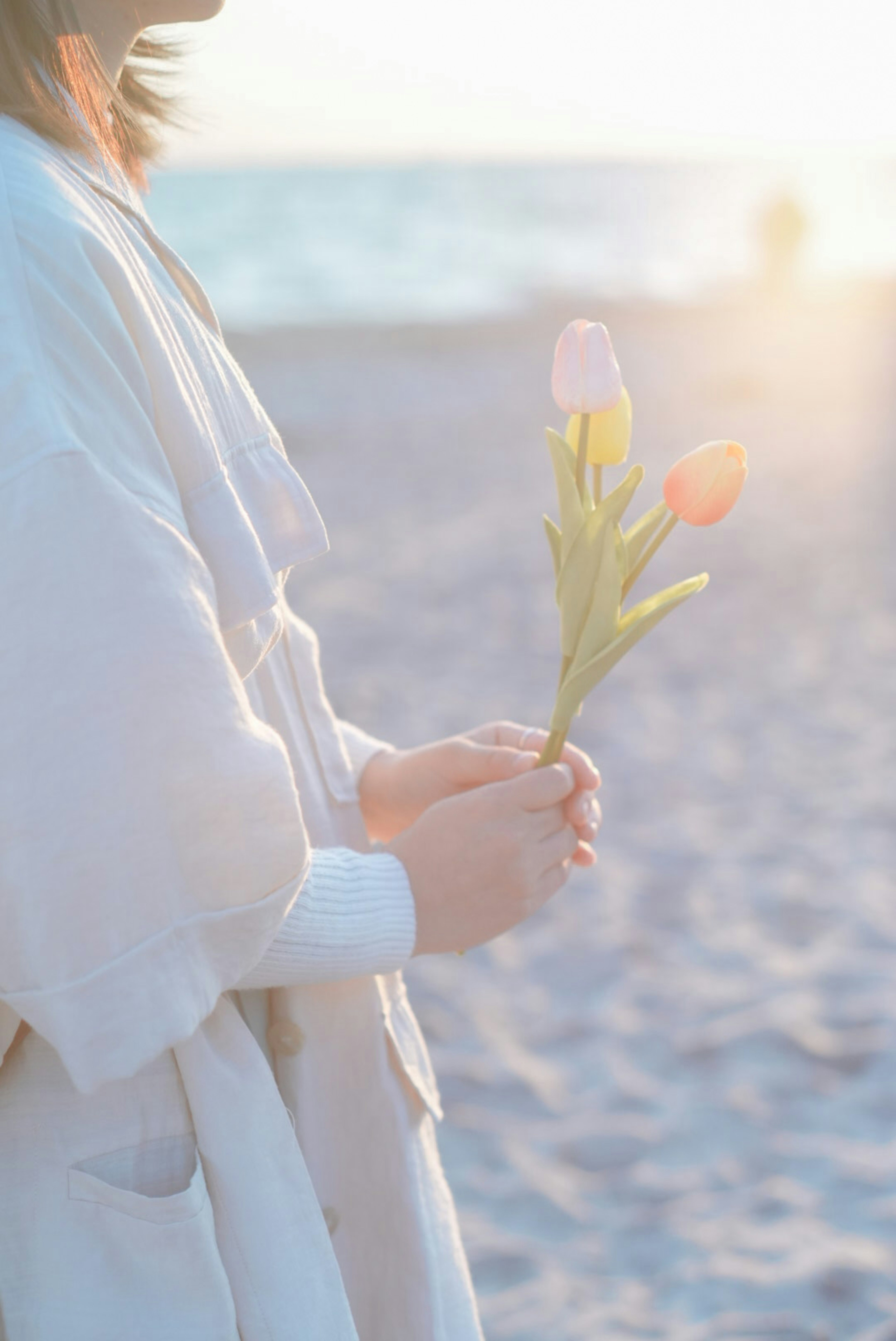 Femme tenant des fleurs au bord de la mer