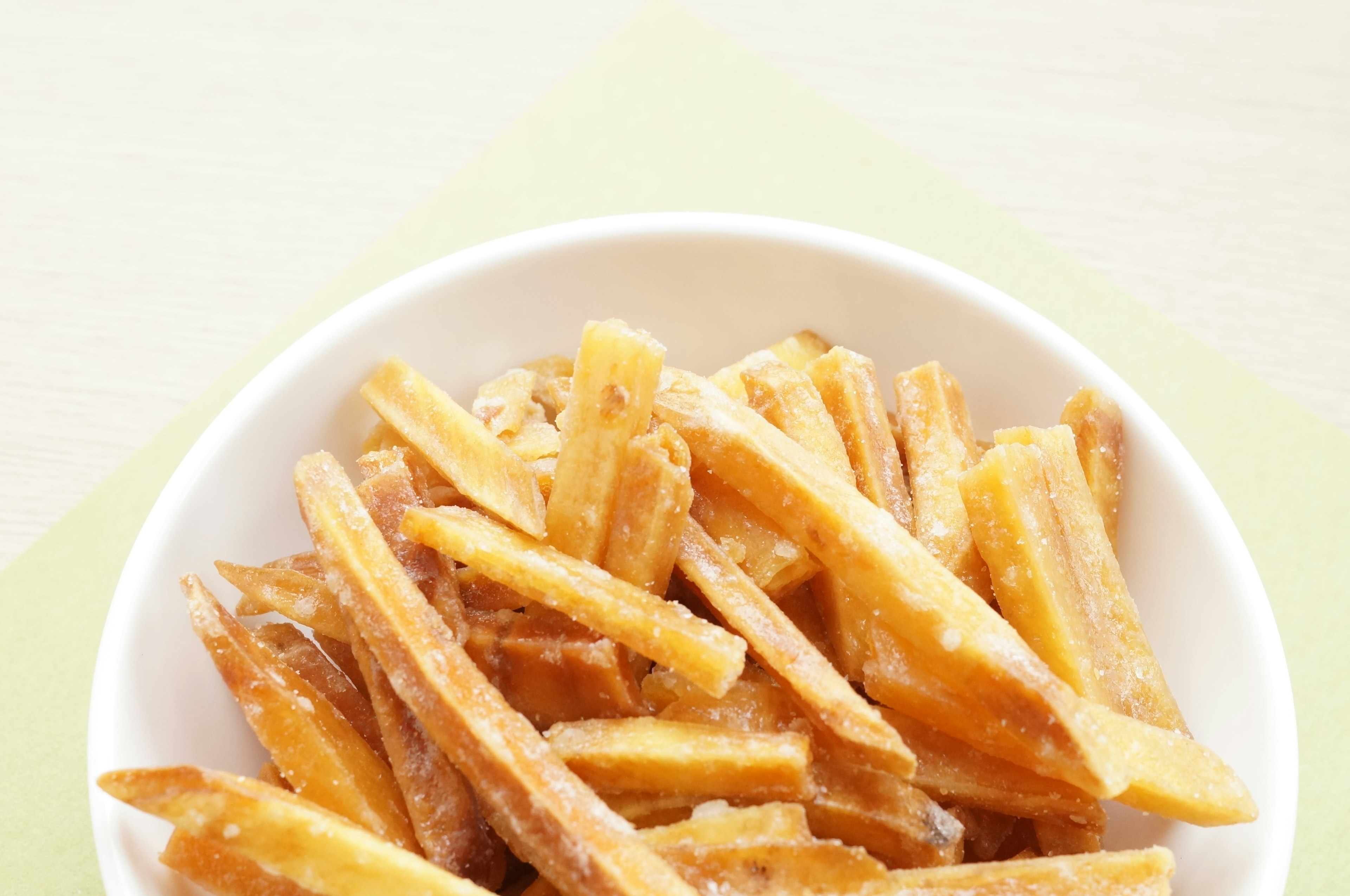 Eine weiße Schüssel mit langen knusprigen frittierten Snacks