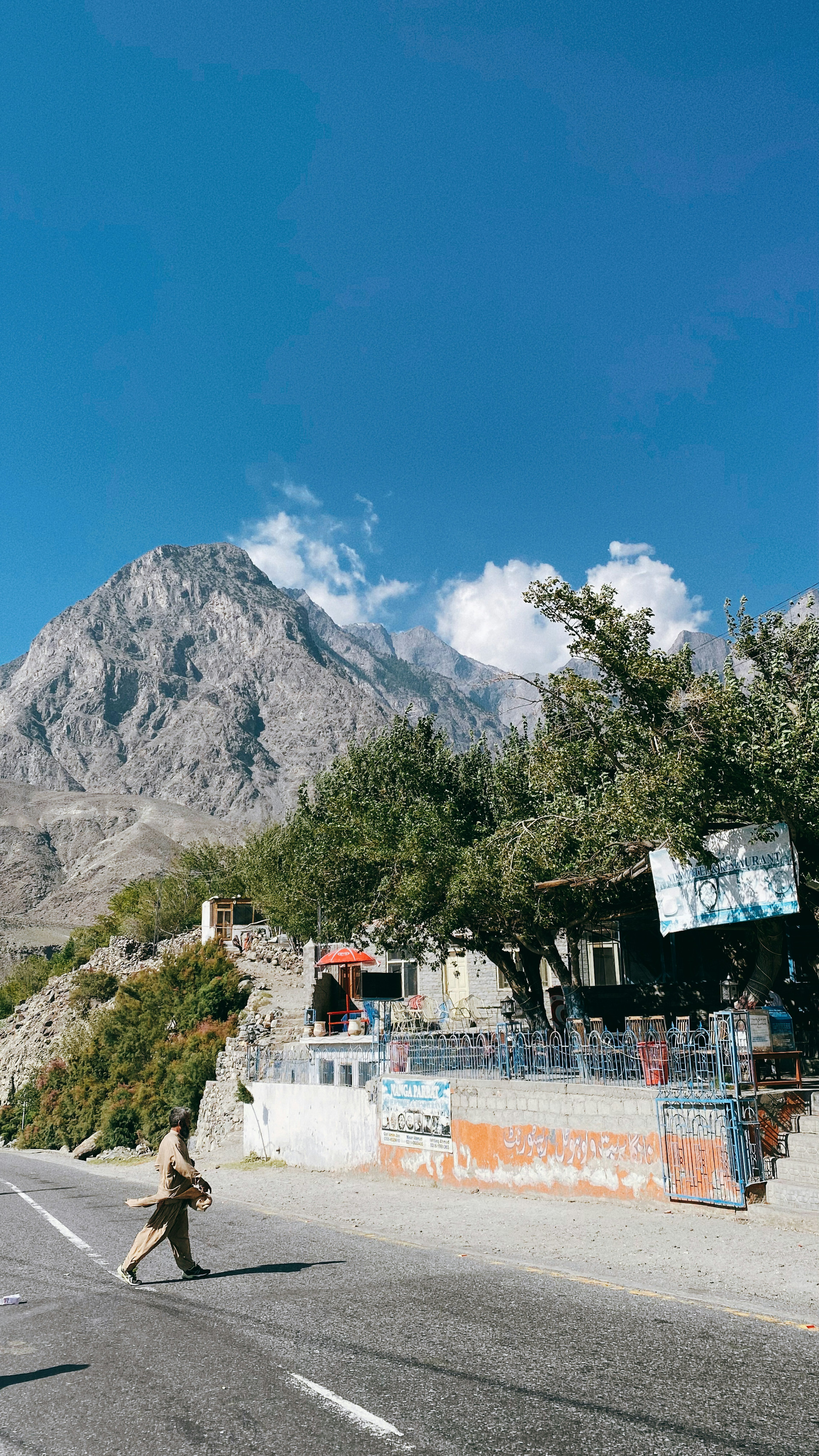 A small building along the road with mountains and blue sky in the background