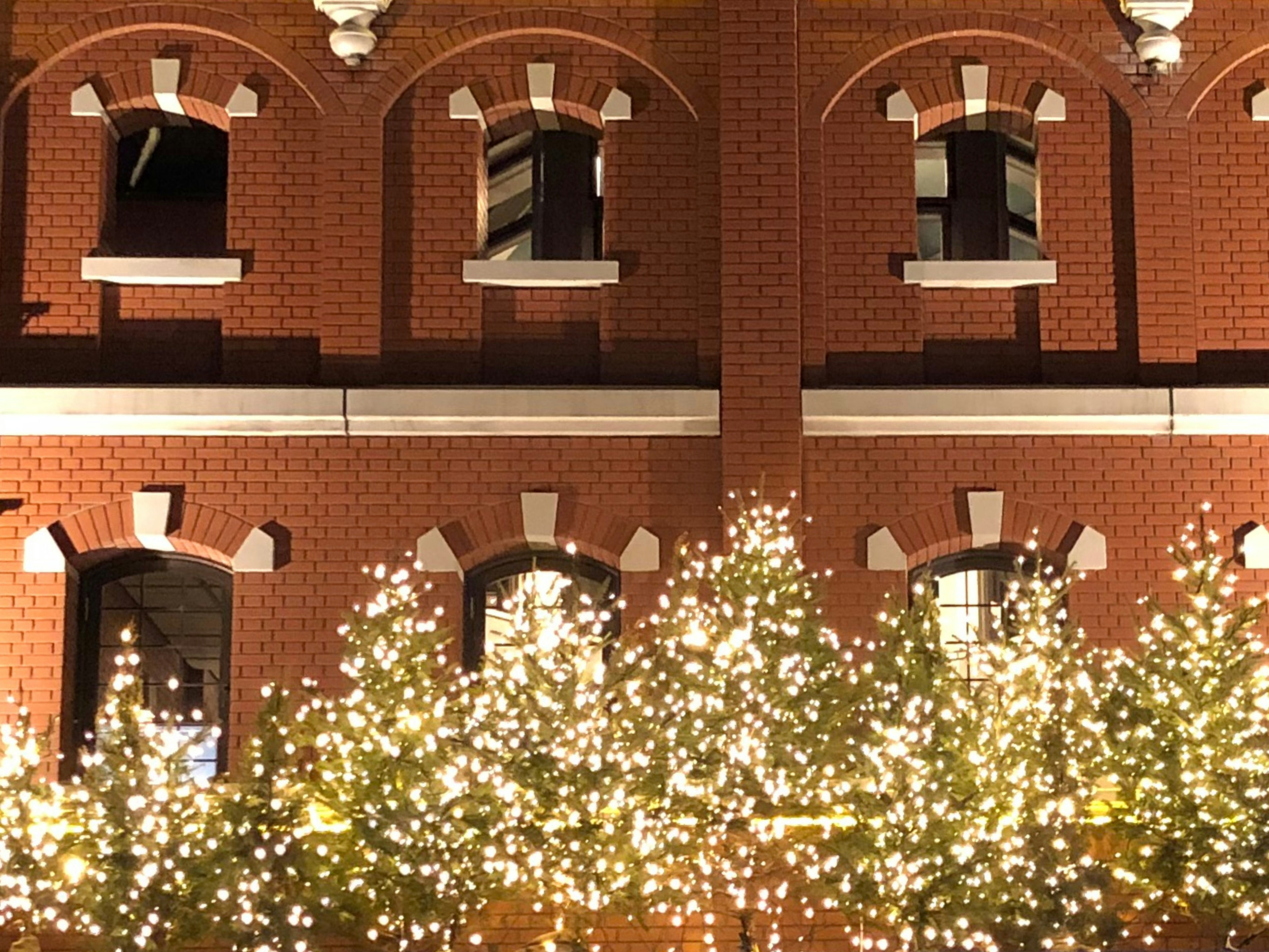 Vista notturna di un edificio in mattoni rossi con archi decorativi e luci illuminate