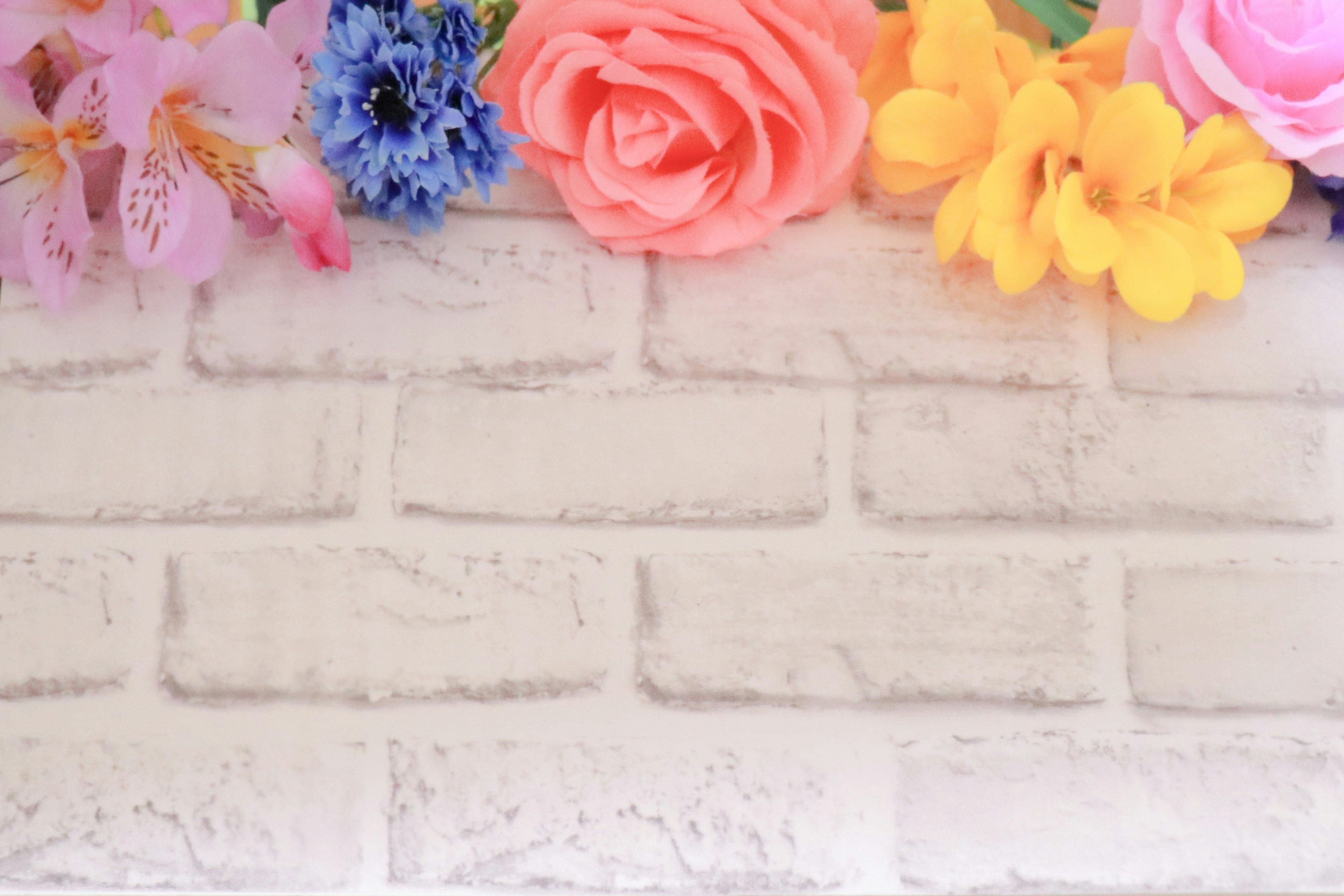 Colorful flowers arranged on a white brick wall