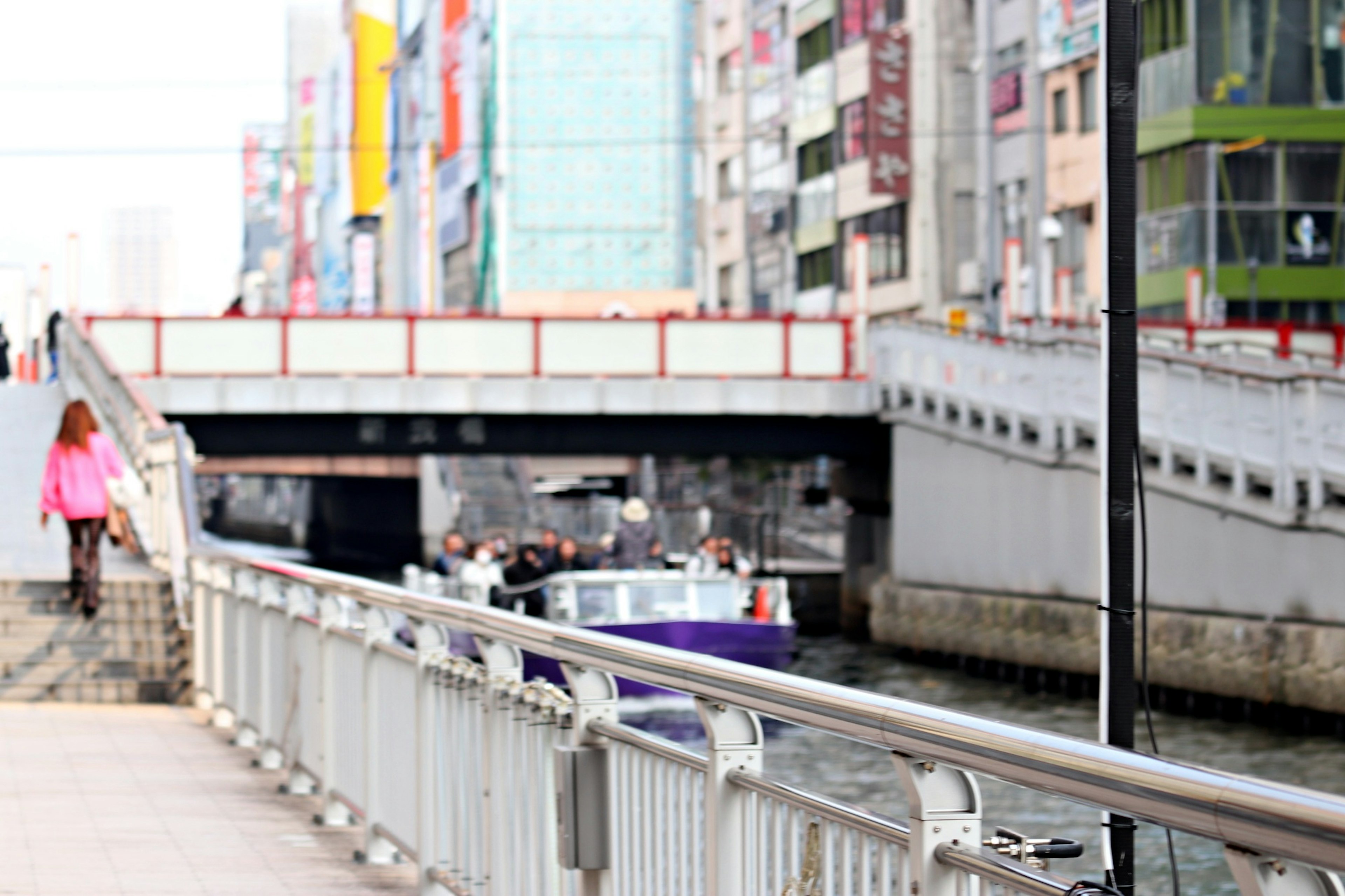 人々が通る歩道と水路の風景 橋の下を通るボート