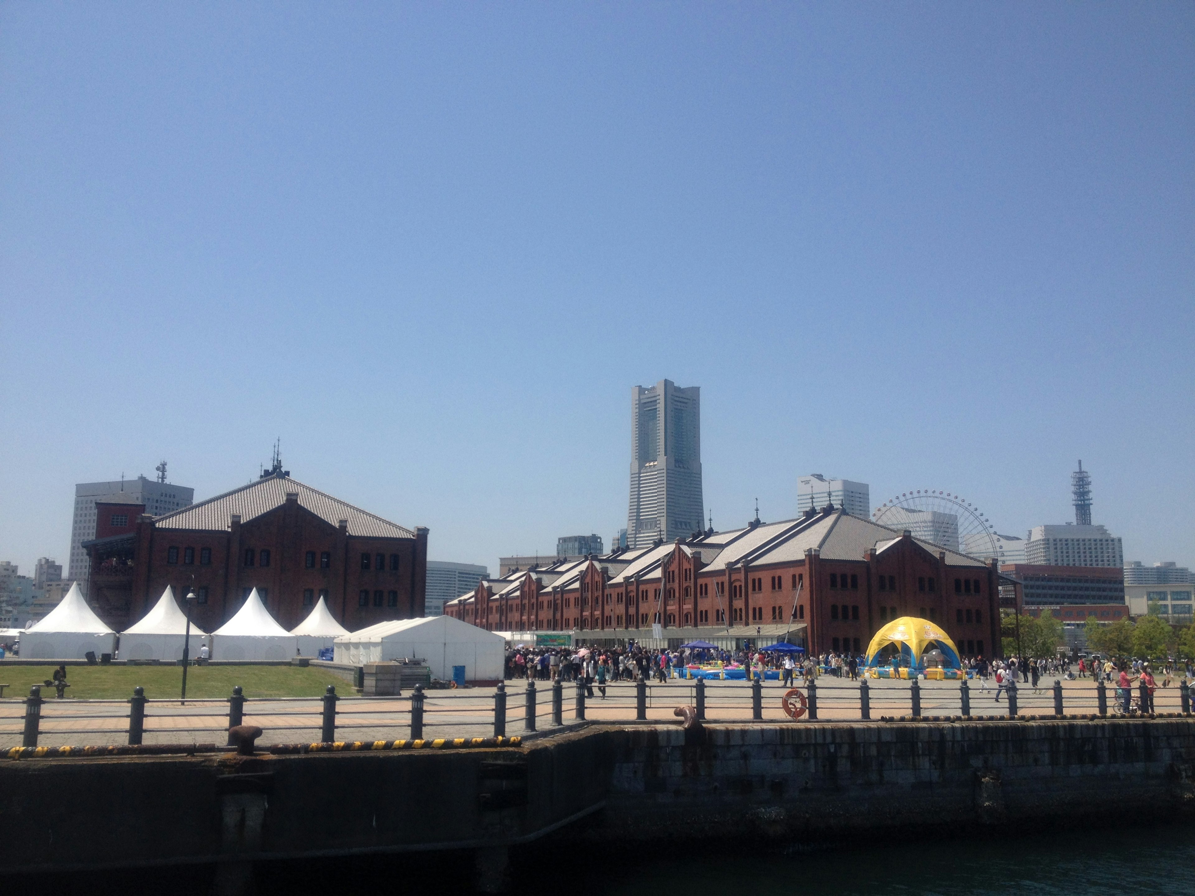 Entrepôt de briques rouges de Yokohama avec des bâtiments modernes en arrière-plan ciel bleu clair et personnes à un événement en plein air