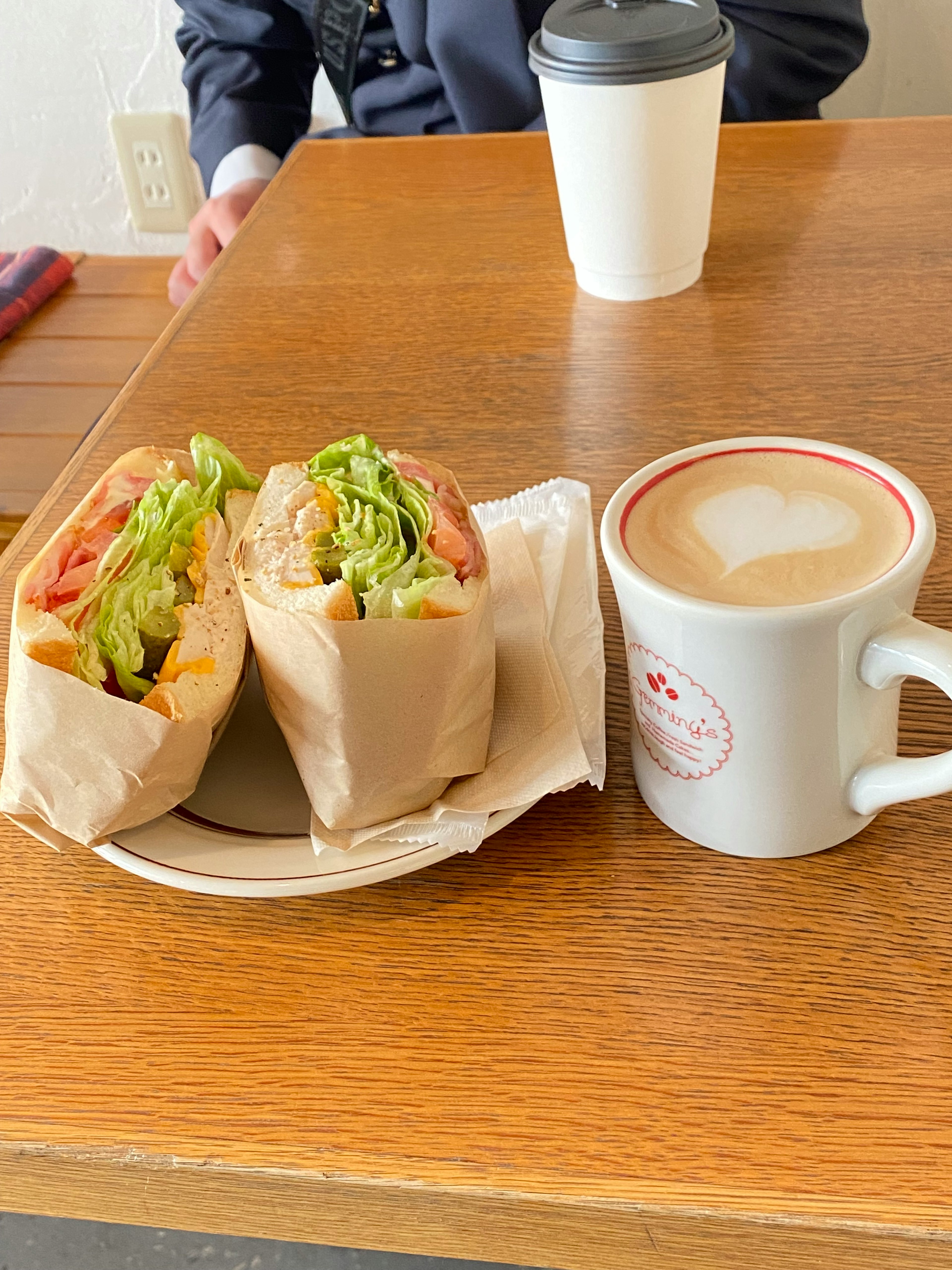 Eine Cafészene mit einem Sandwich und einer Tasse Kaffee auf einem Holztisch