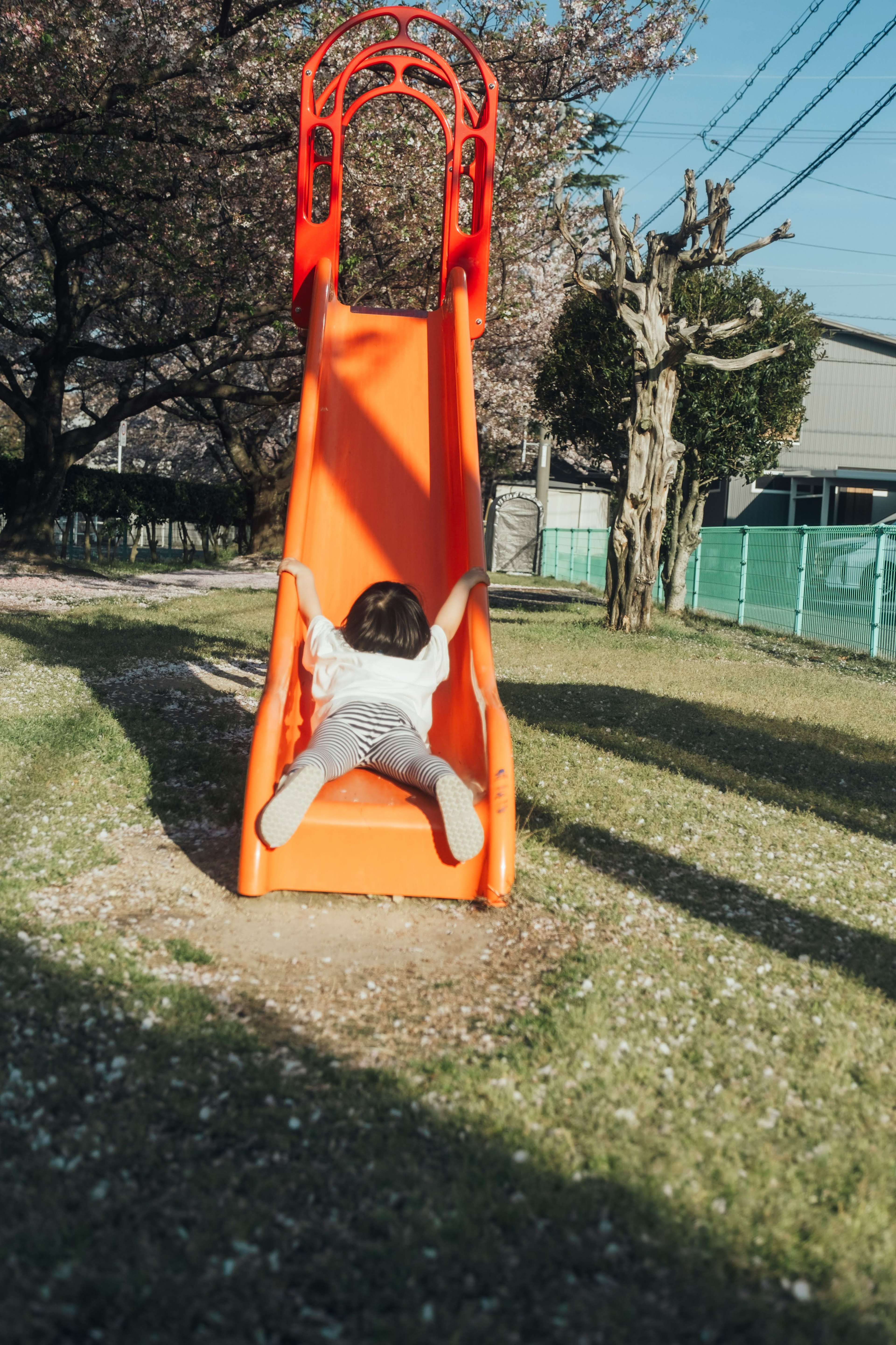 Un bambino che gioca su uno scivolo arancione in un parco