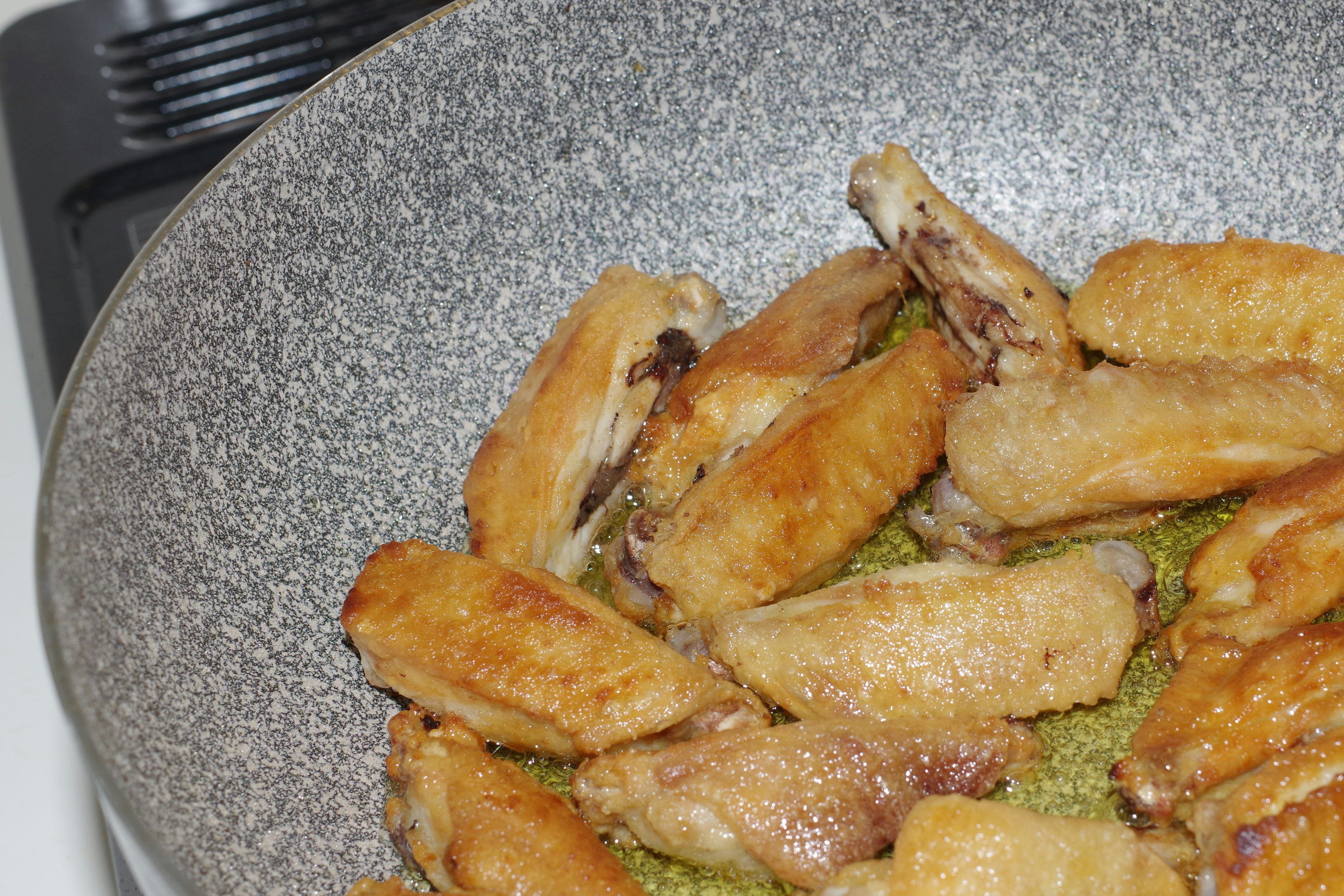 Close-up of crispy chicken wings cooking in a frying pan